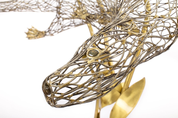 A figurative steel and brass sculpture of an Otter swimming through reeds and water.