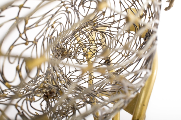 A figurative steel and brass sculpture of an Otter swimming through reeds and water.