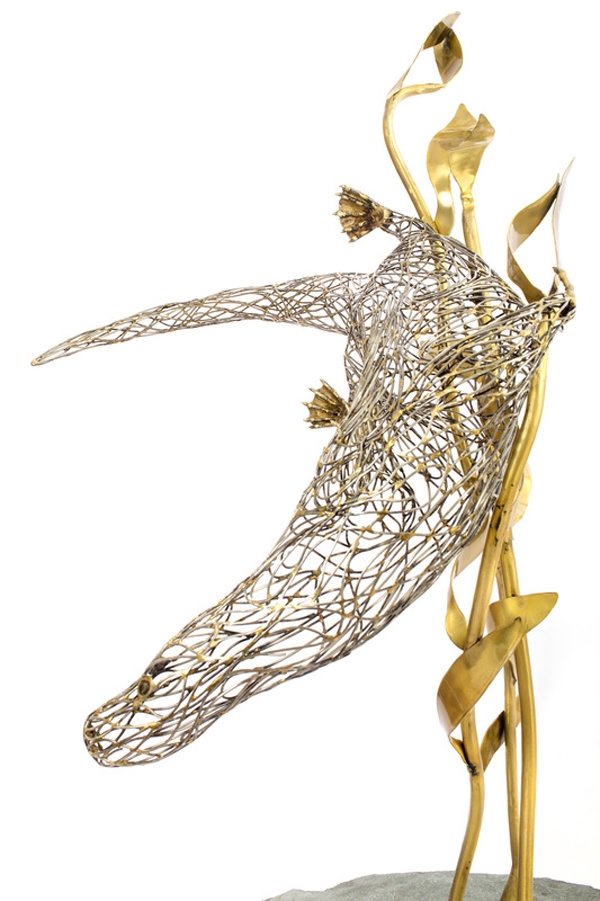 A figurative steel and brass sculpture of an Otter swimming through reeds and water.