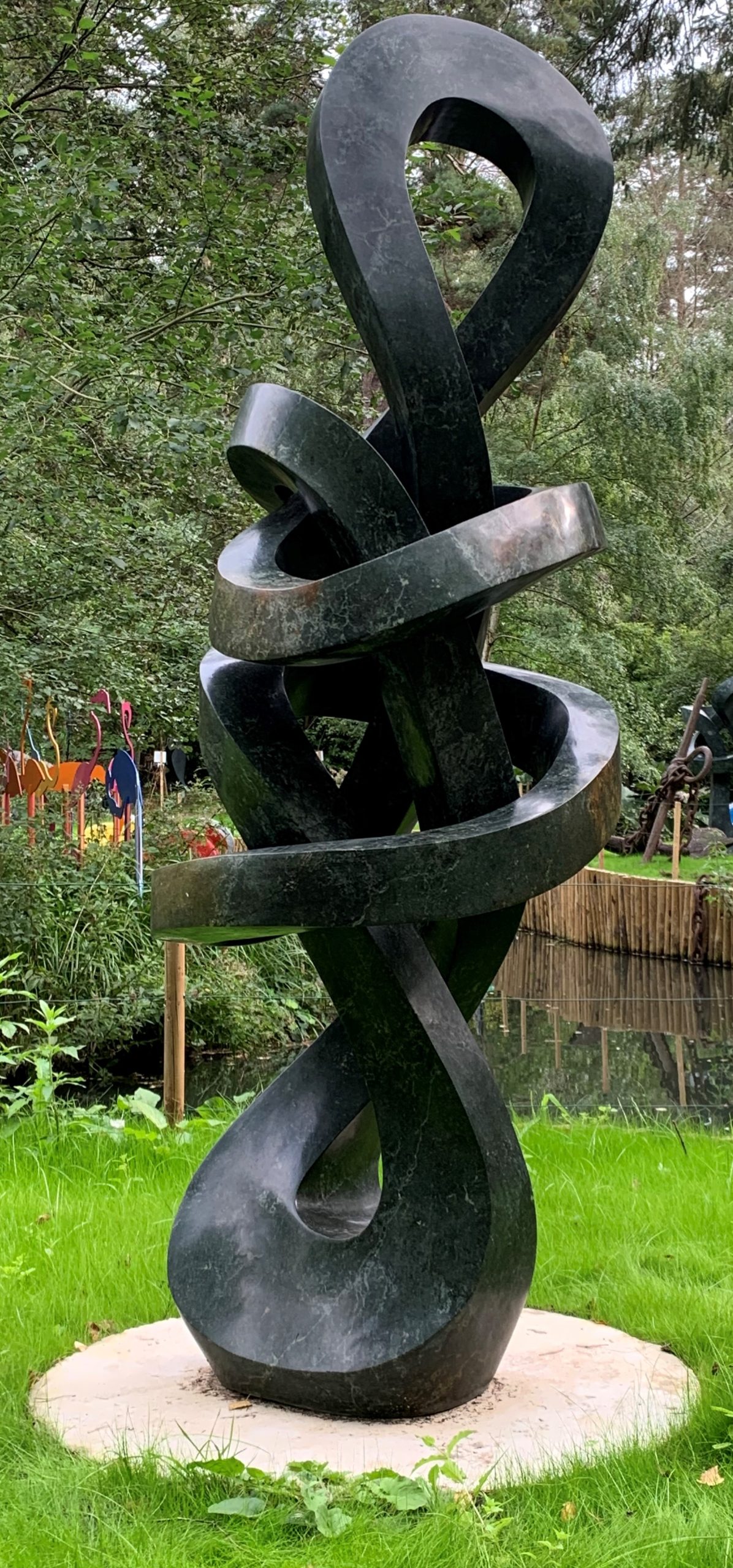 A shona opal stone sculpture of a twisting and looping abstract shape.