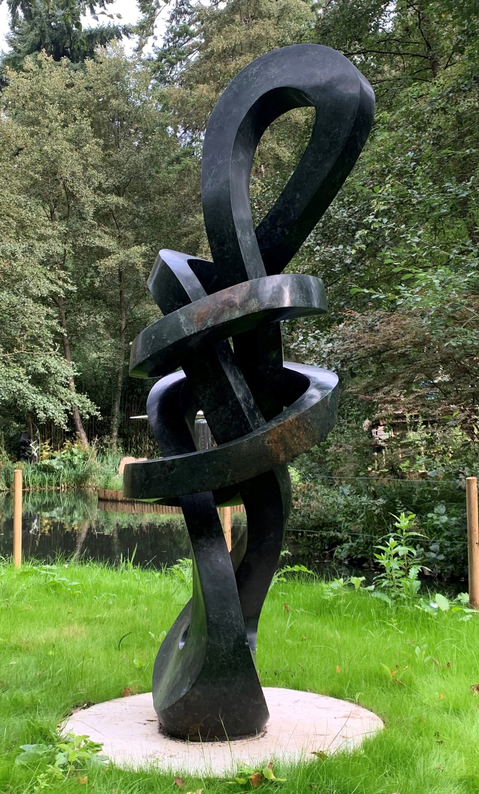 A shona opal stone sculpture of a twisting and looping abstract shape.