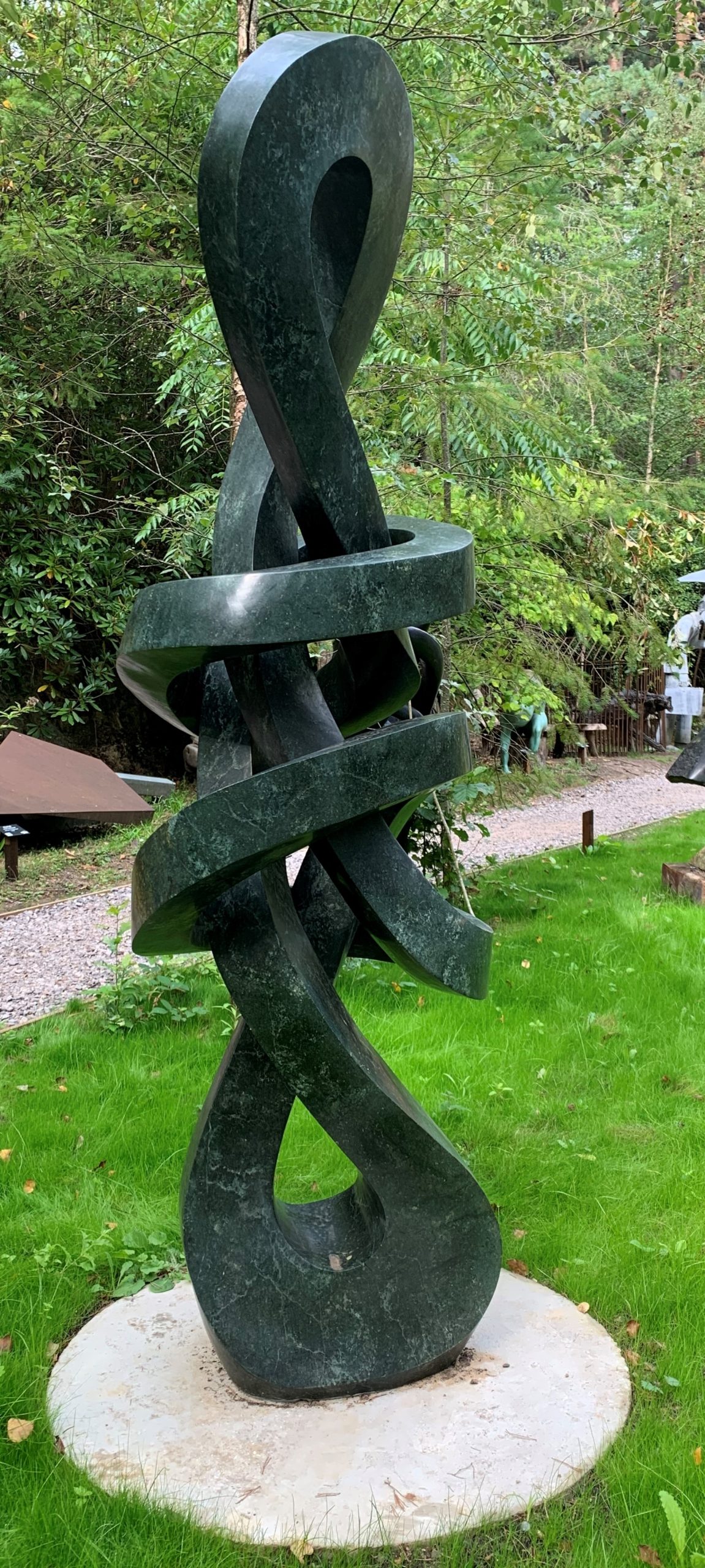 A shona opal stone sculpture of a twisting and looping abstract shape.