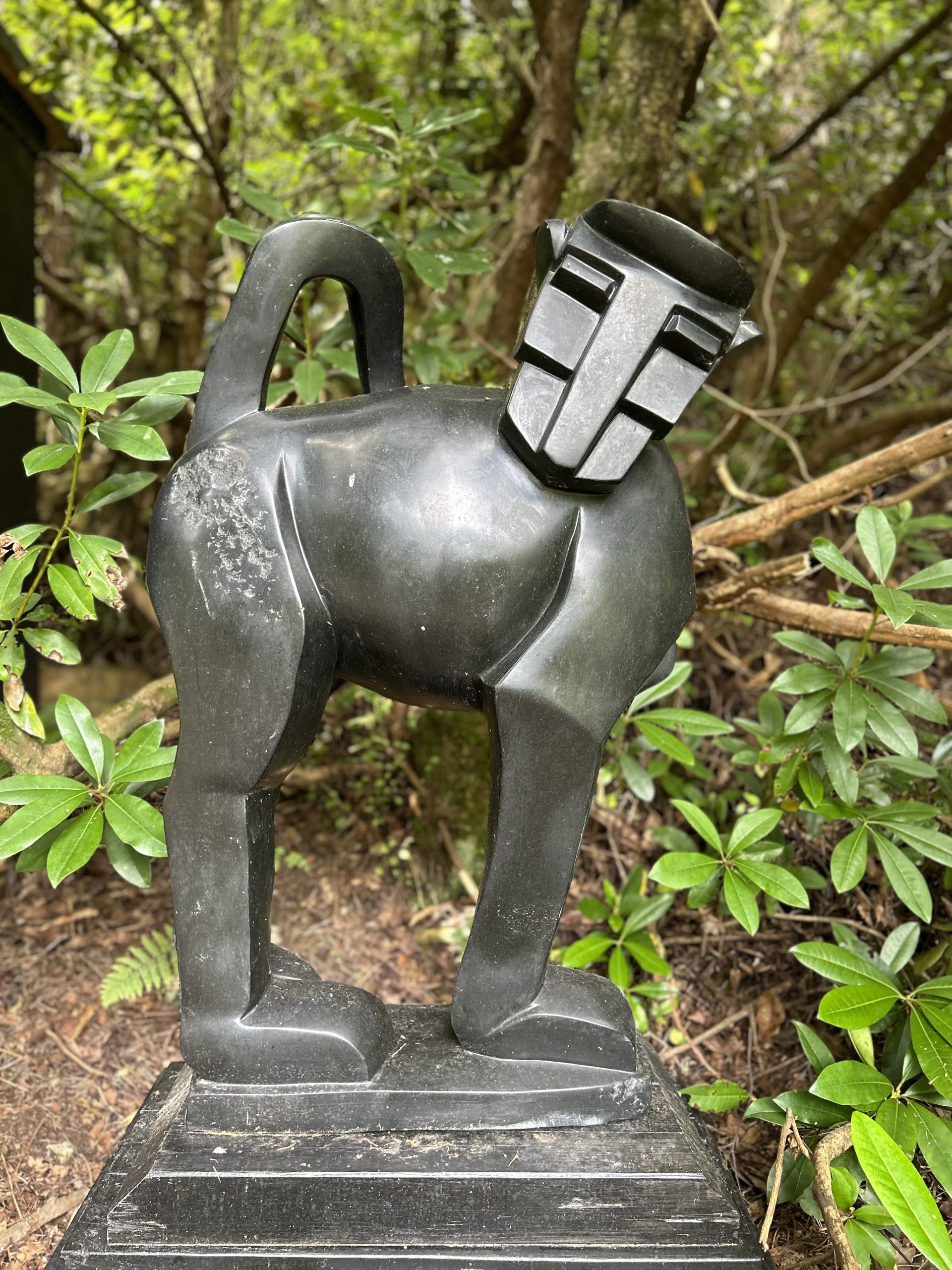 A contemporary stone sculpture of a baboon standing on top of a slab.