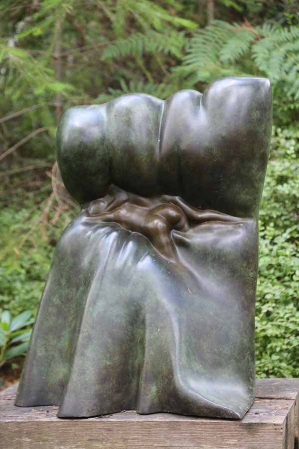 A abstract bronze sculpture of a pair of figures laying down with each other.