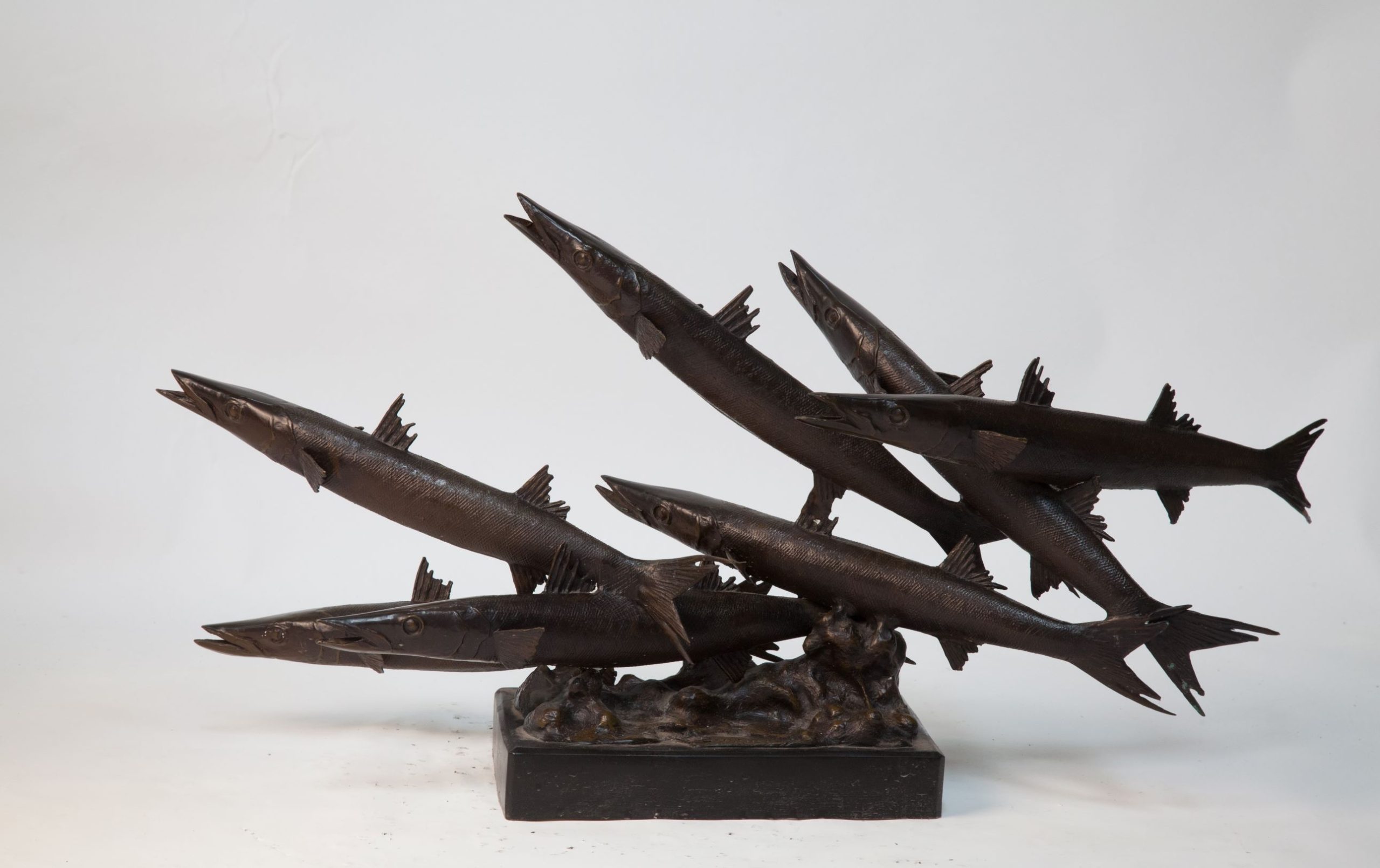 A smaller scale bronze sculpture of 6 barracuda swimming.