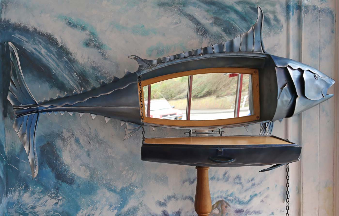 A figurative steel and wood sculpture of a drinks cabinet in the shape of a tuna fish.