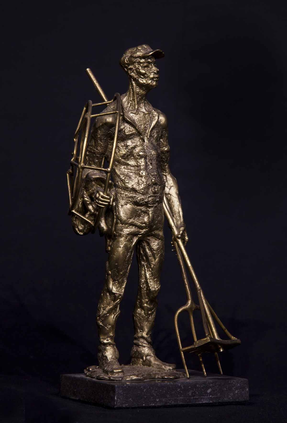 A figurative bronze sculpture of a man holding various gardening equipment.