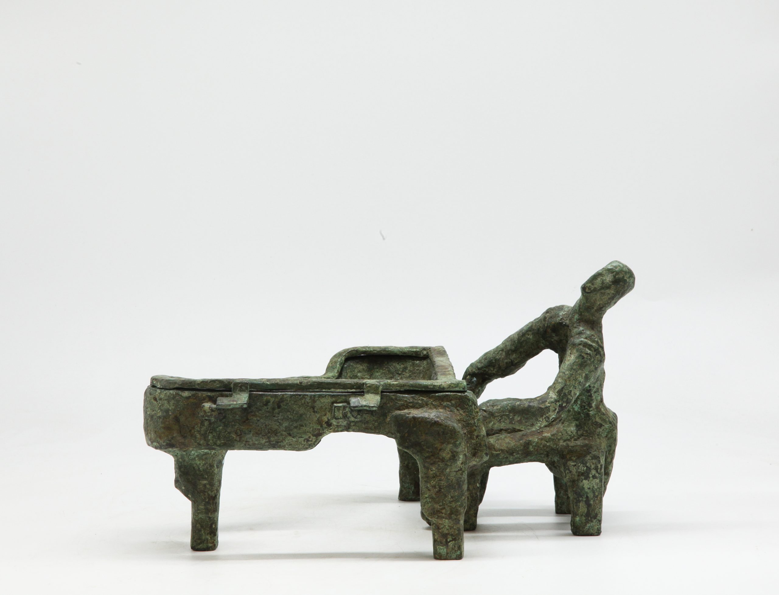 A bronze abstract sculpture of a person sitting down and playing a grand piano.