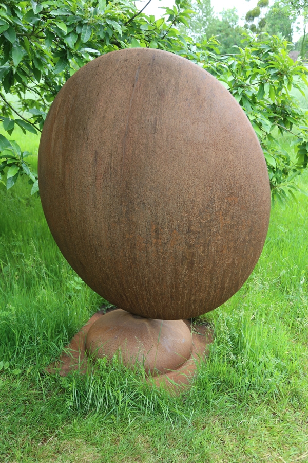 A abstract steel sculpture of a giant brown round moon.