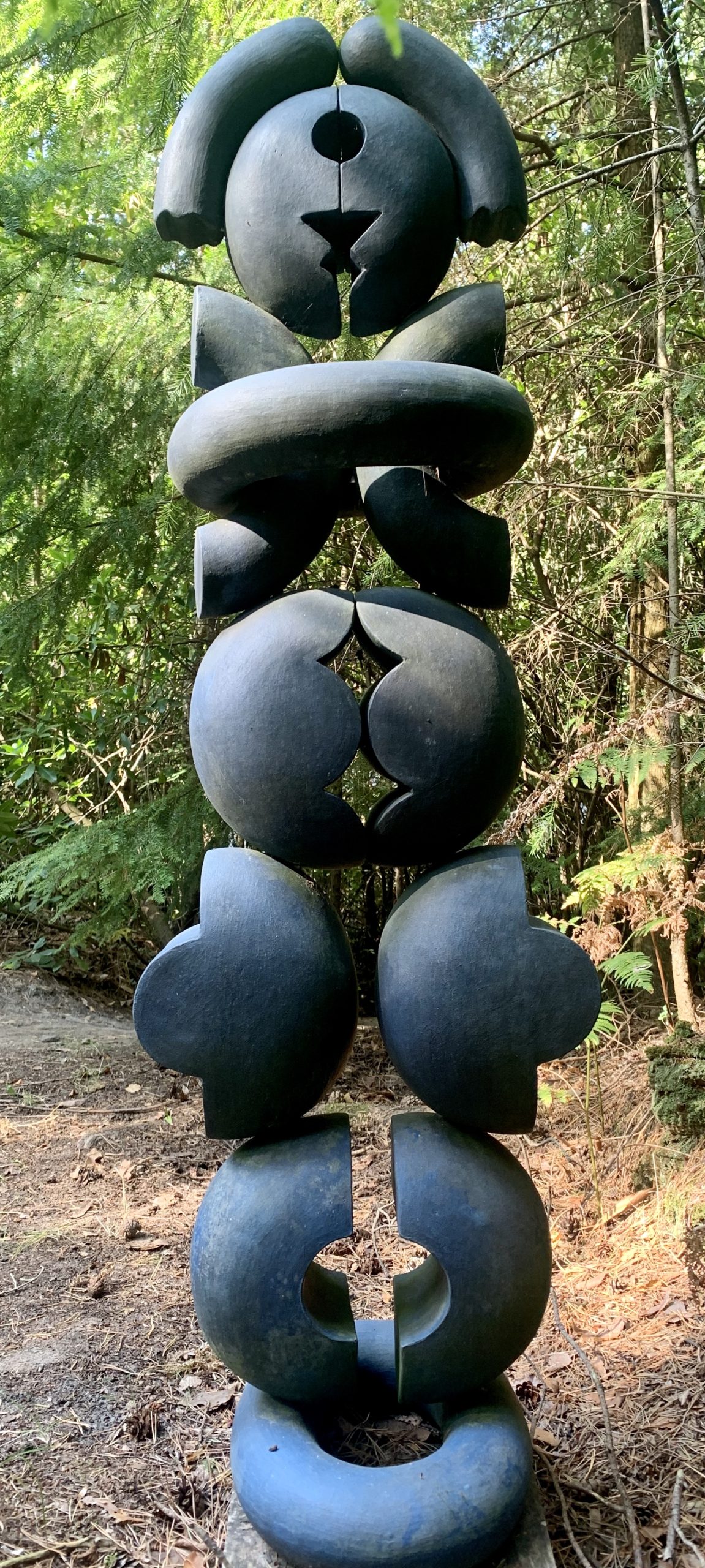 A abstract stone and wood sculpture of a variety of shaped stacked on top of each other.