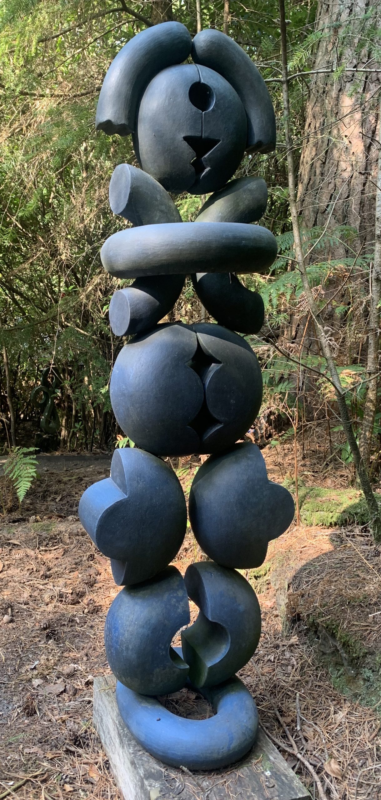 A abstract stone and wood sculpture of a variety of shaped stacked on top of each other.