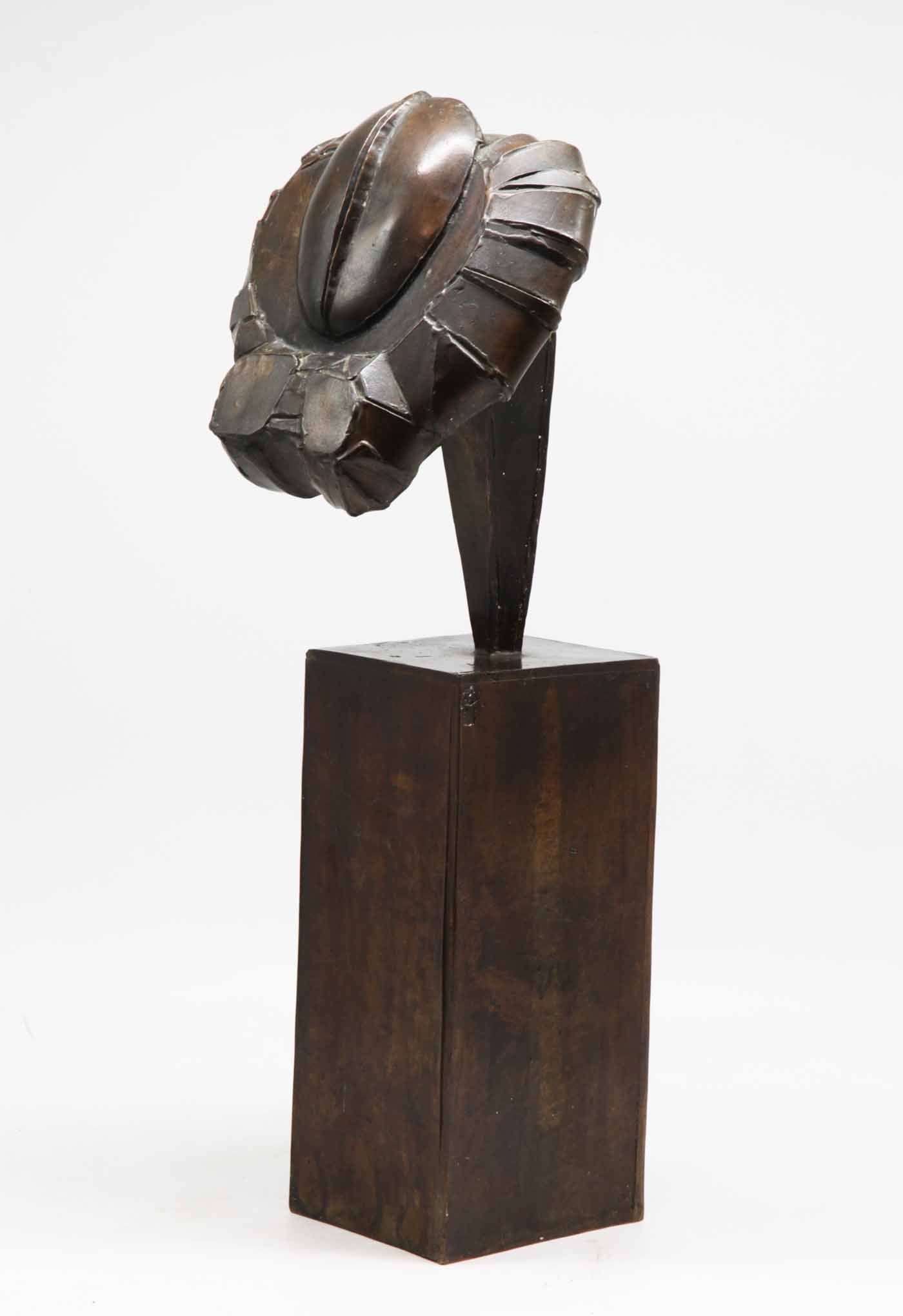 A abstract bronze sculpture of a shape on top of a block.