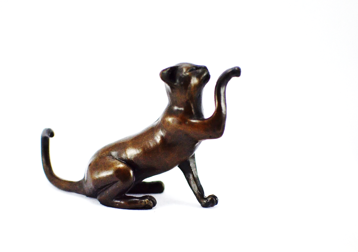 A smaller scale bronze sculpture of a cat with it's paw held up.
