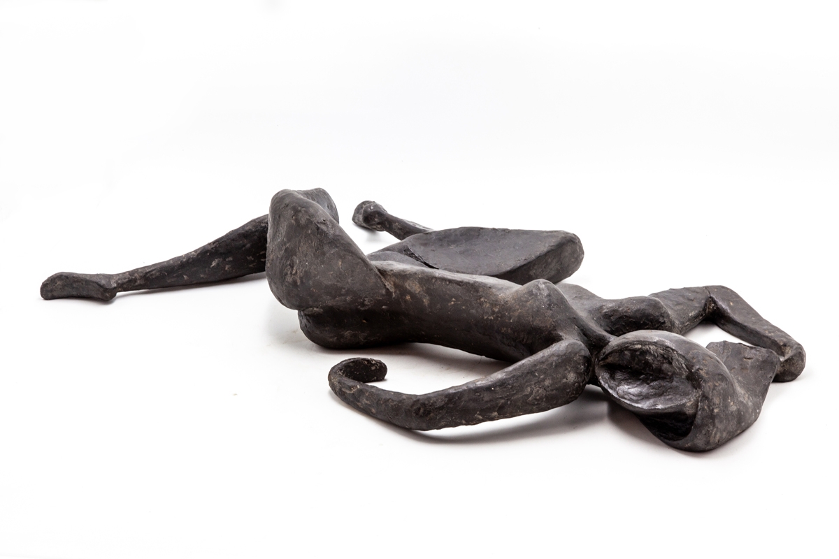 A figurative bronze resin sculpture of a abstract woman lying on her back.