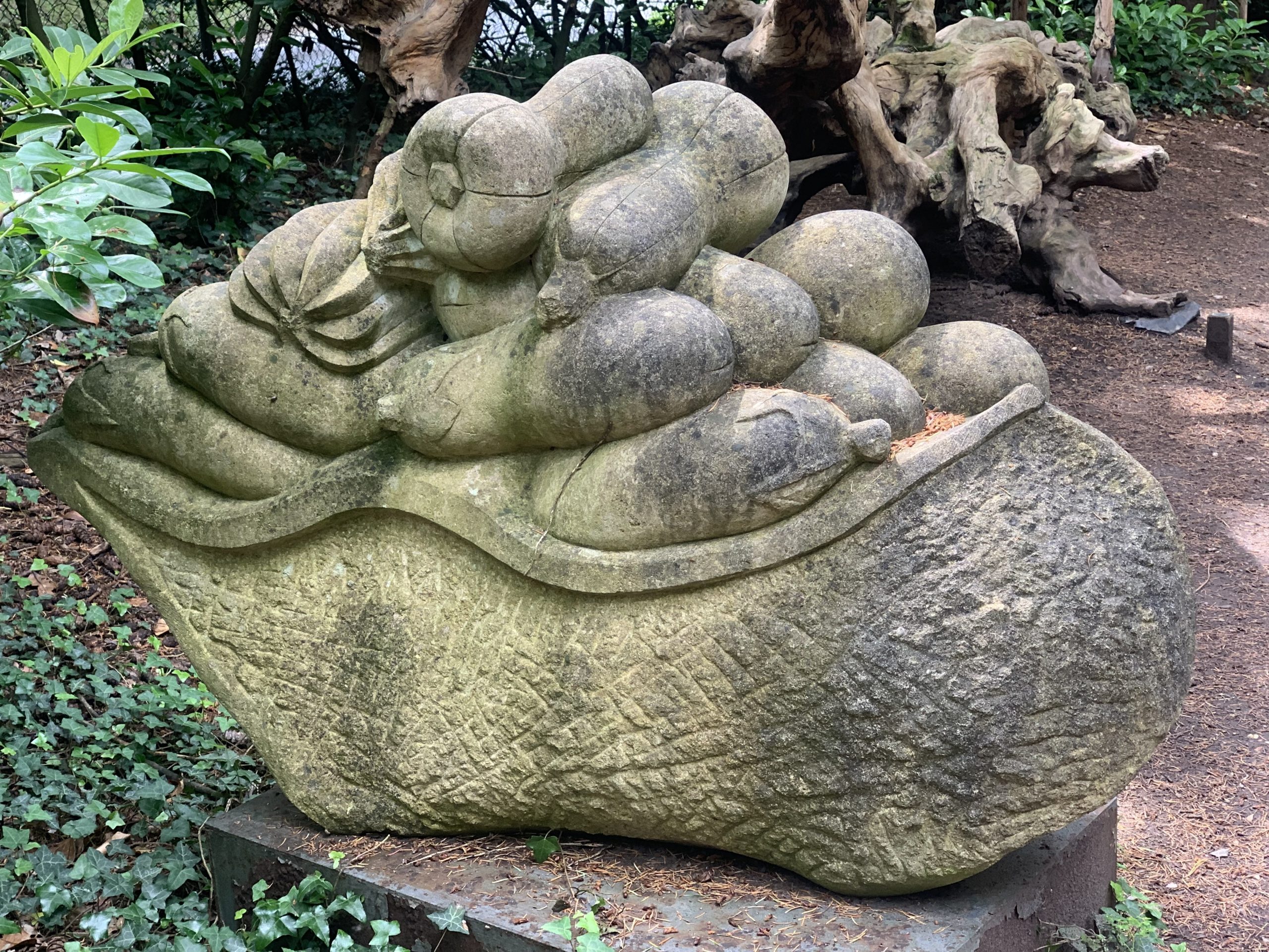 A decorative stone sculpture of a basket carrying a variety of vegetables.
