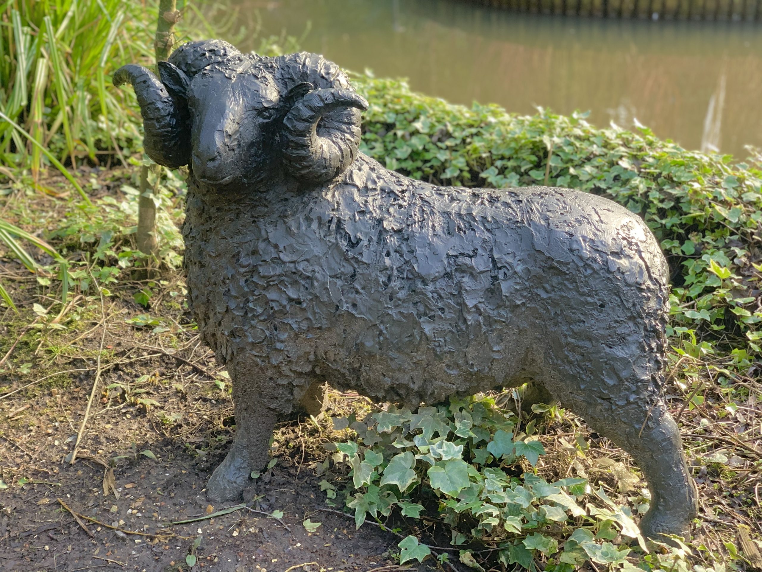 A figurative bronze sculpture of a ram with a wide stance.