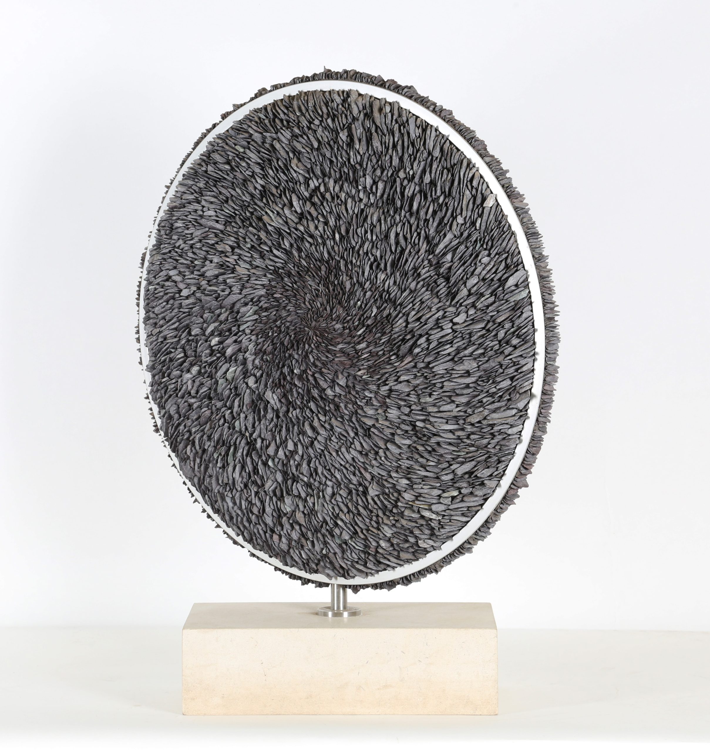 A contemporary stone and metal sculpture of a circle filled with pieces of slate.