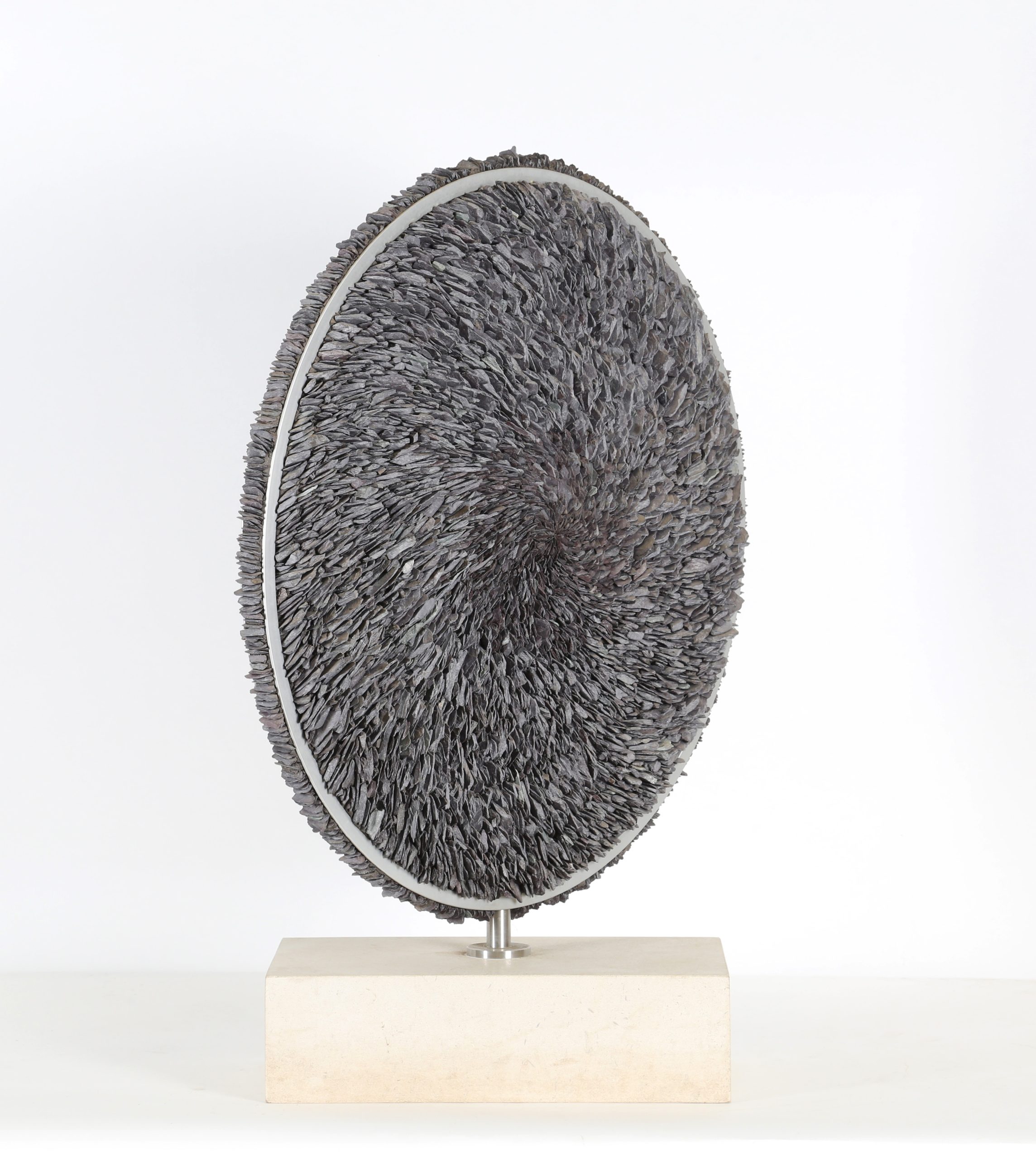 A contemporary stone and metal sculpture of a circle filled with pieces of slate.