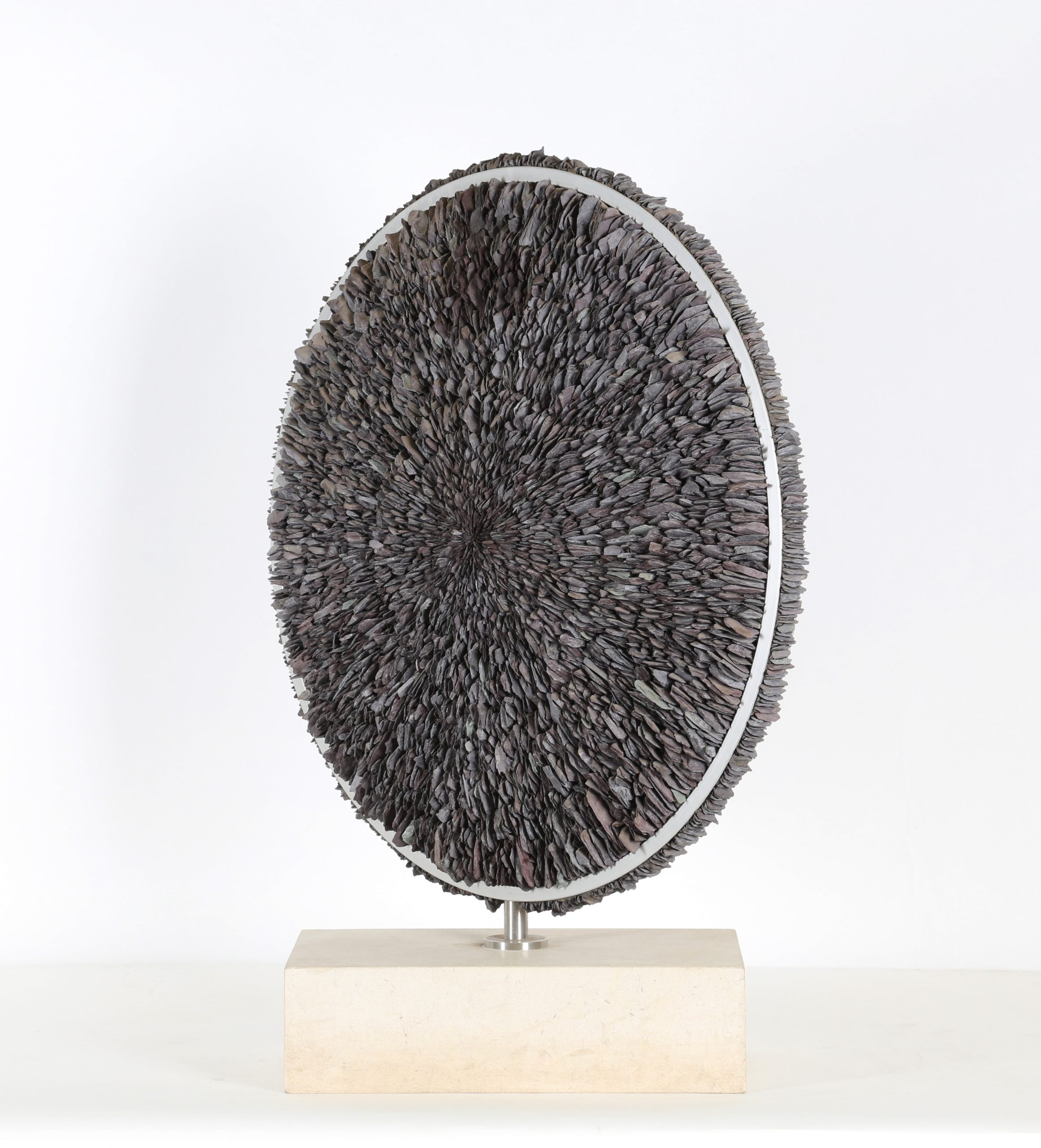 A contemporary stone and metal sculpture of a circle filled with pieces of slate.