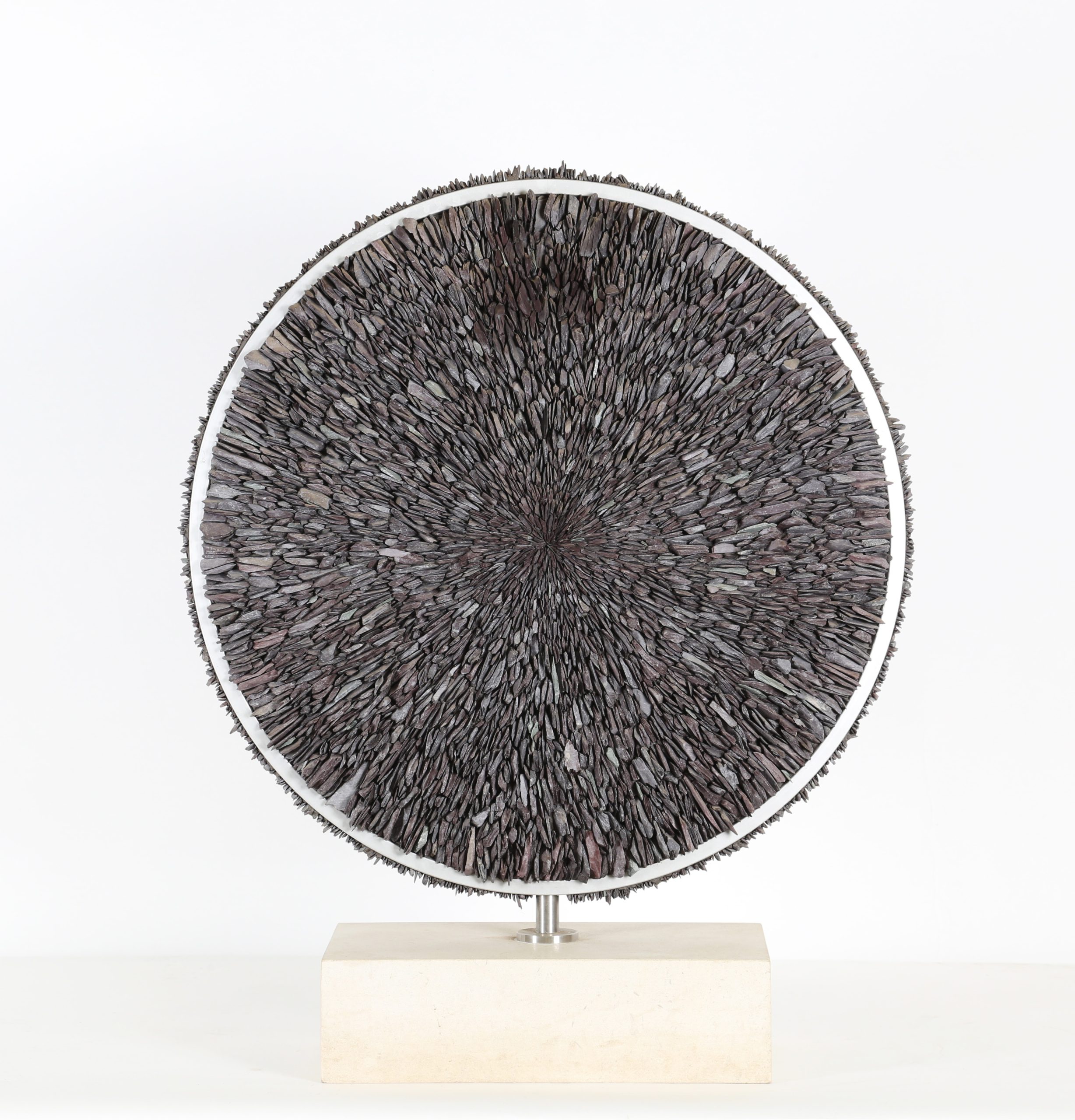 A contemporary stone and metal sculpture of a circle filled with pieces of slate.