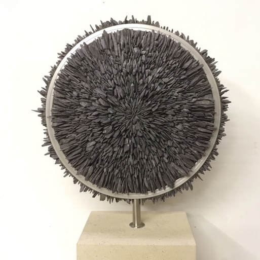 A contemporary stone and metal sculpture of a circle filled with pieces of slate.