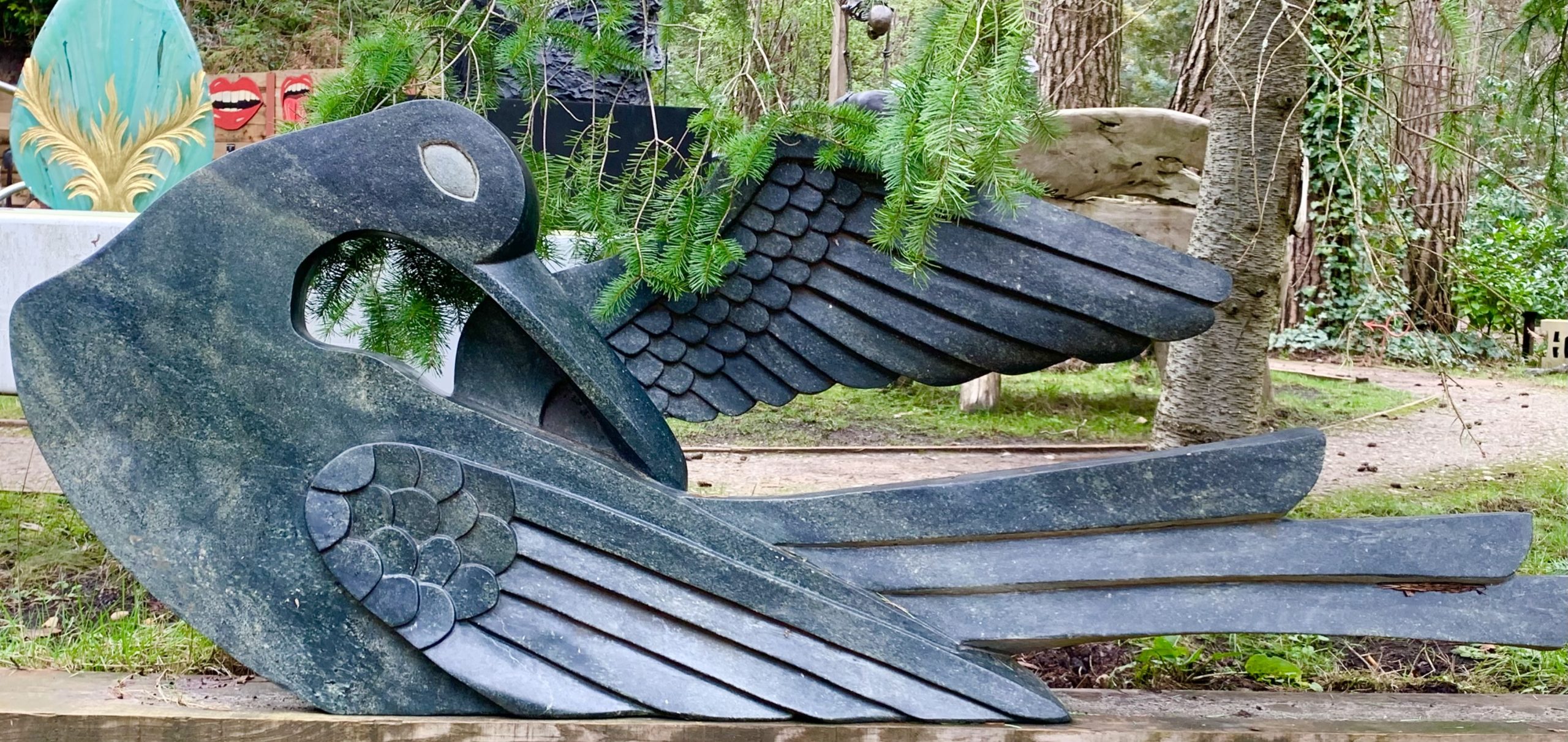 A Shona opal stone sculpture of a bird with its head back and one wing open.