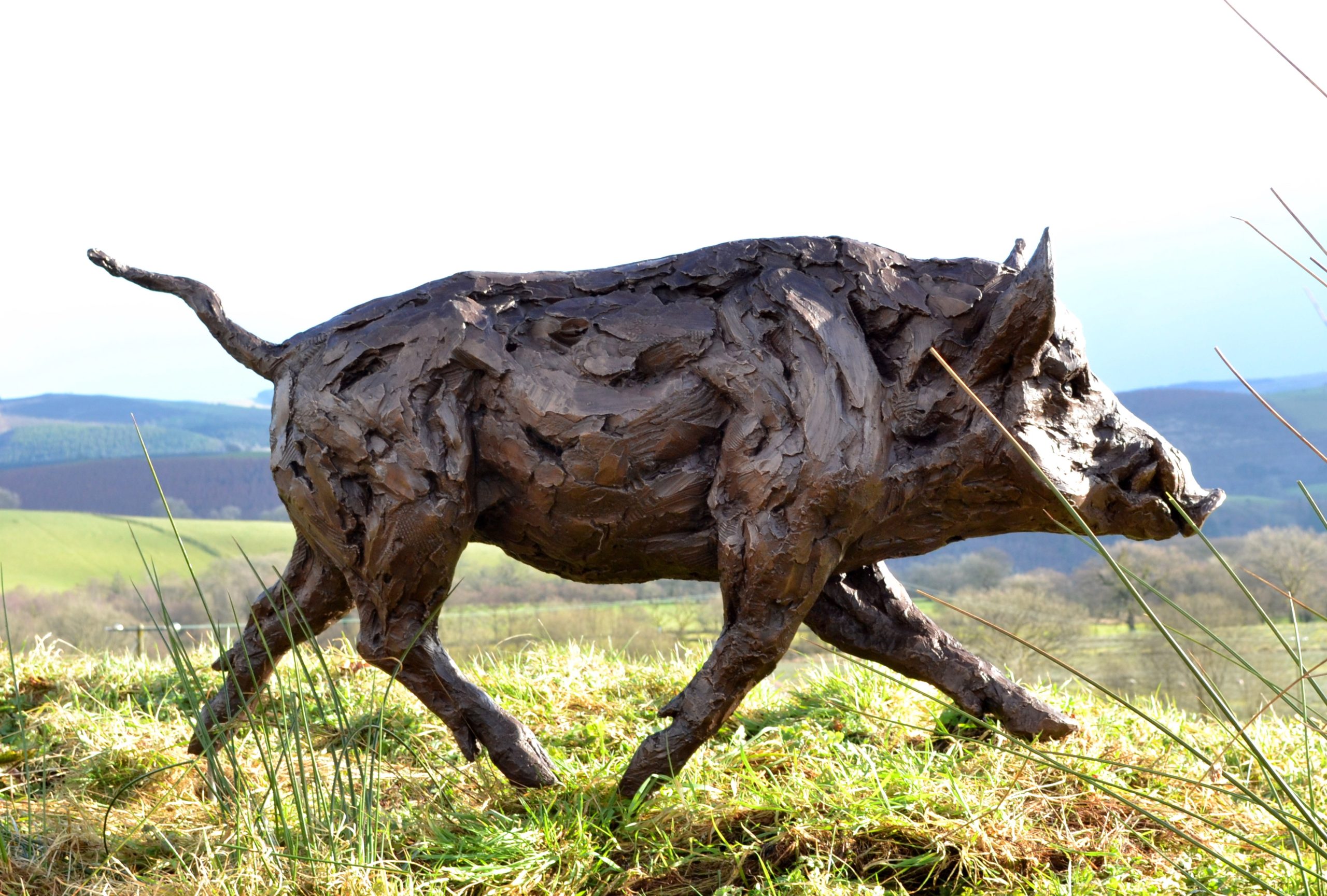 A realism bronze resin sculpture of a wild boar running.