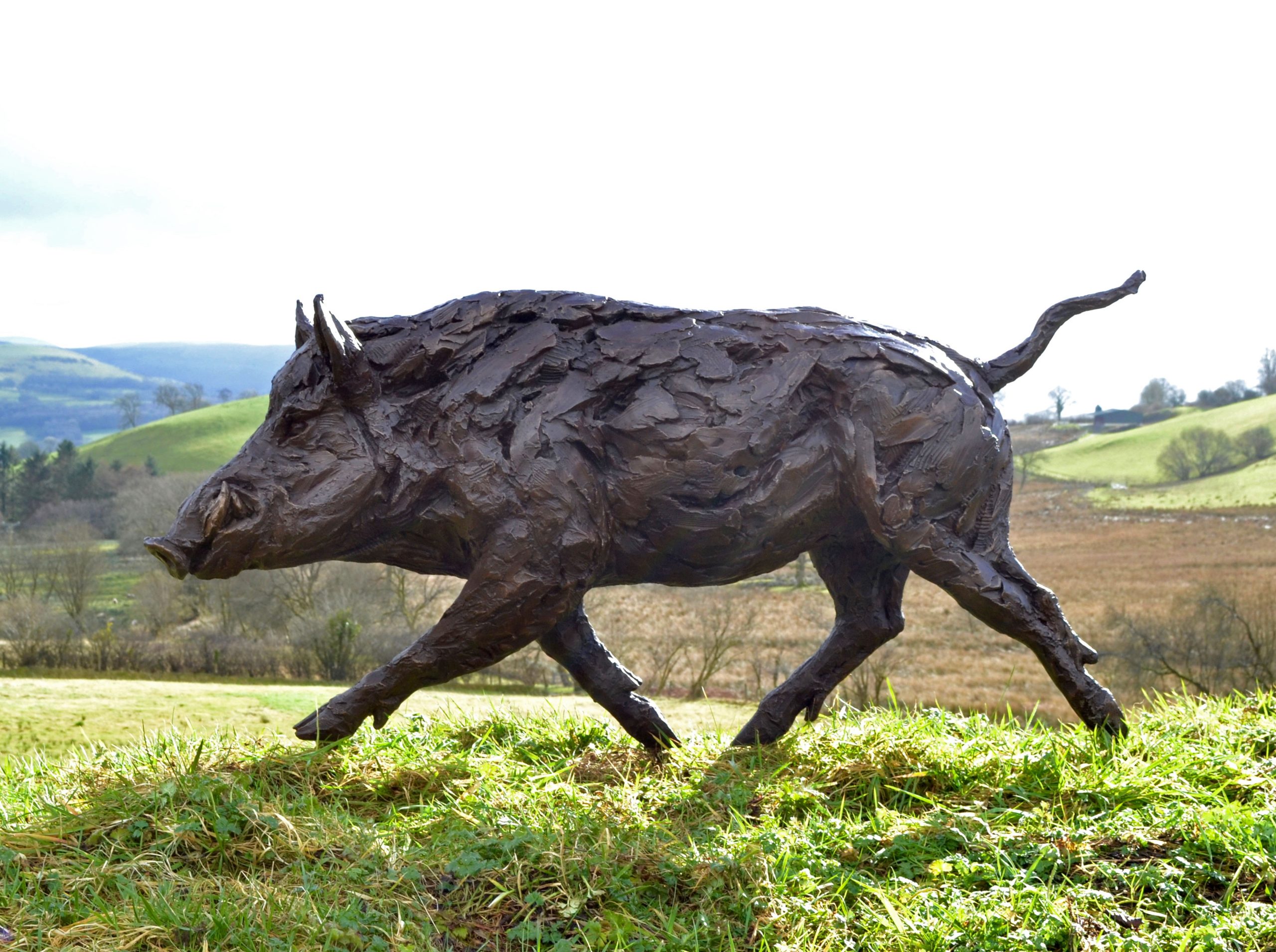 A realism bronze resin sculpture of a wild boar running.