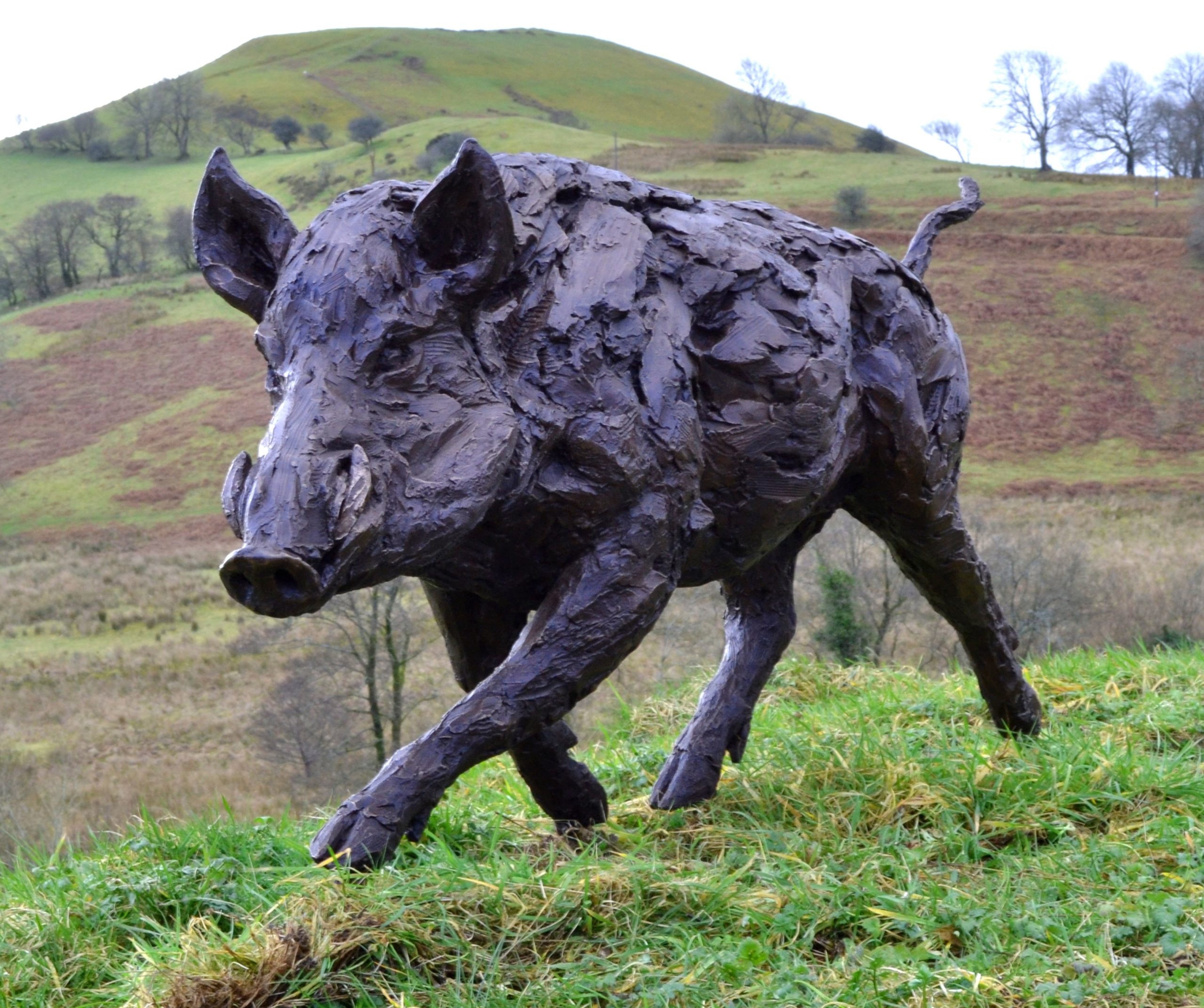 A realism bronze resin sculpture of a wild boar running.