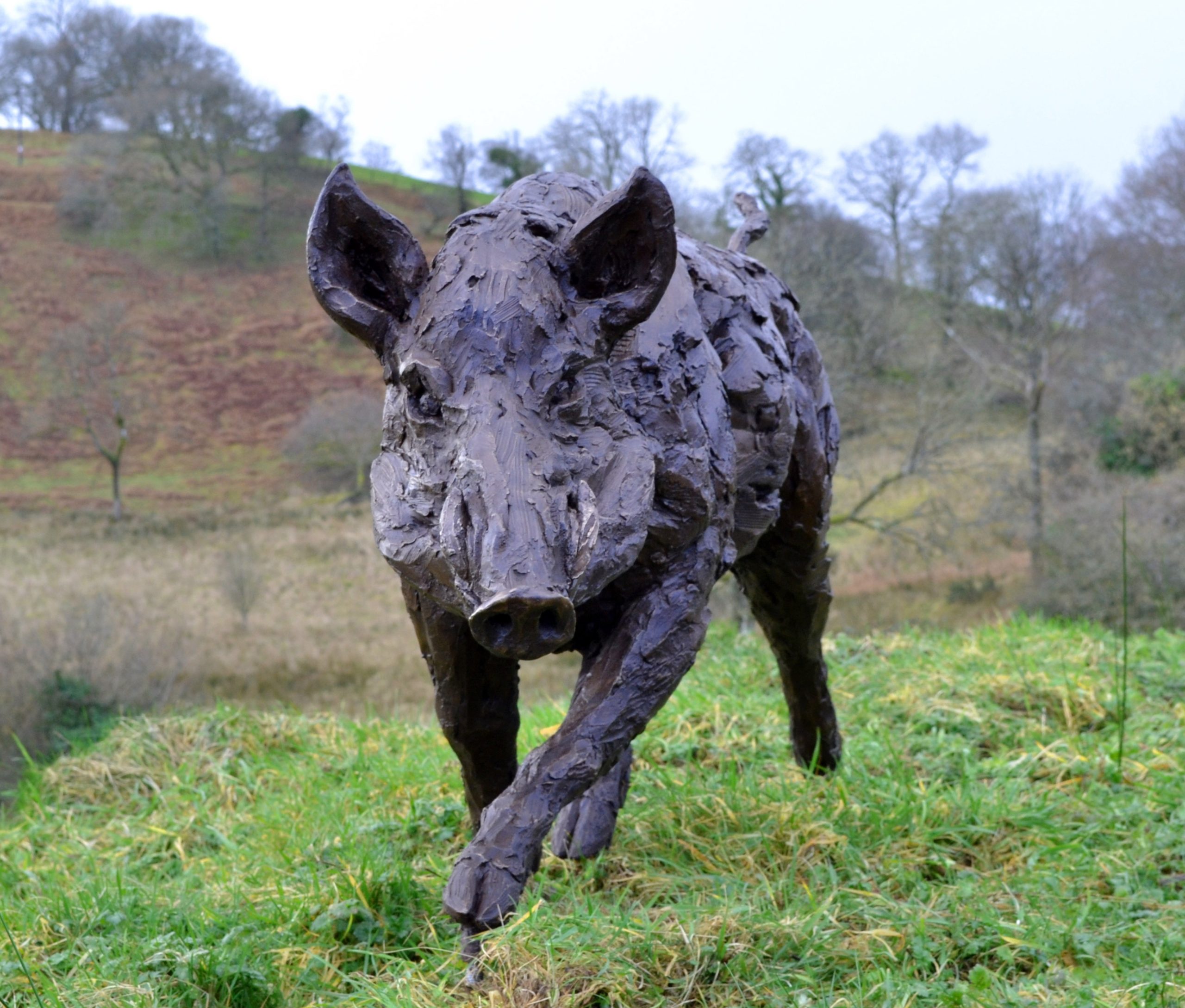 A realism bronze resin sculpture of a wild boar running.