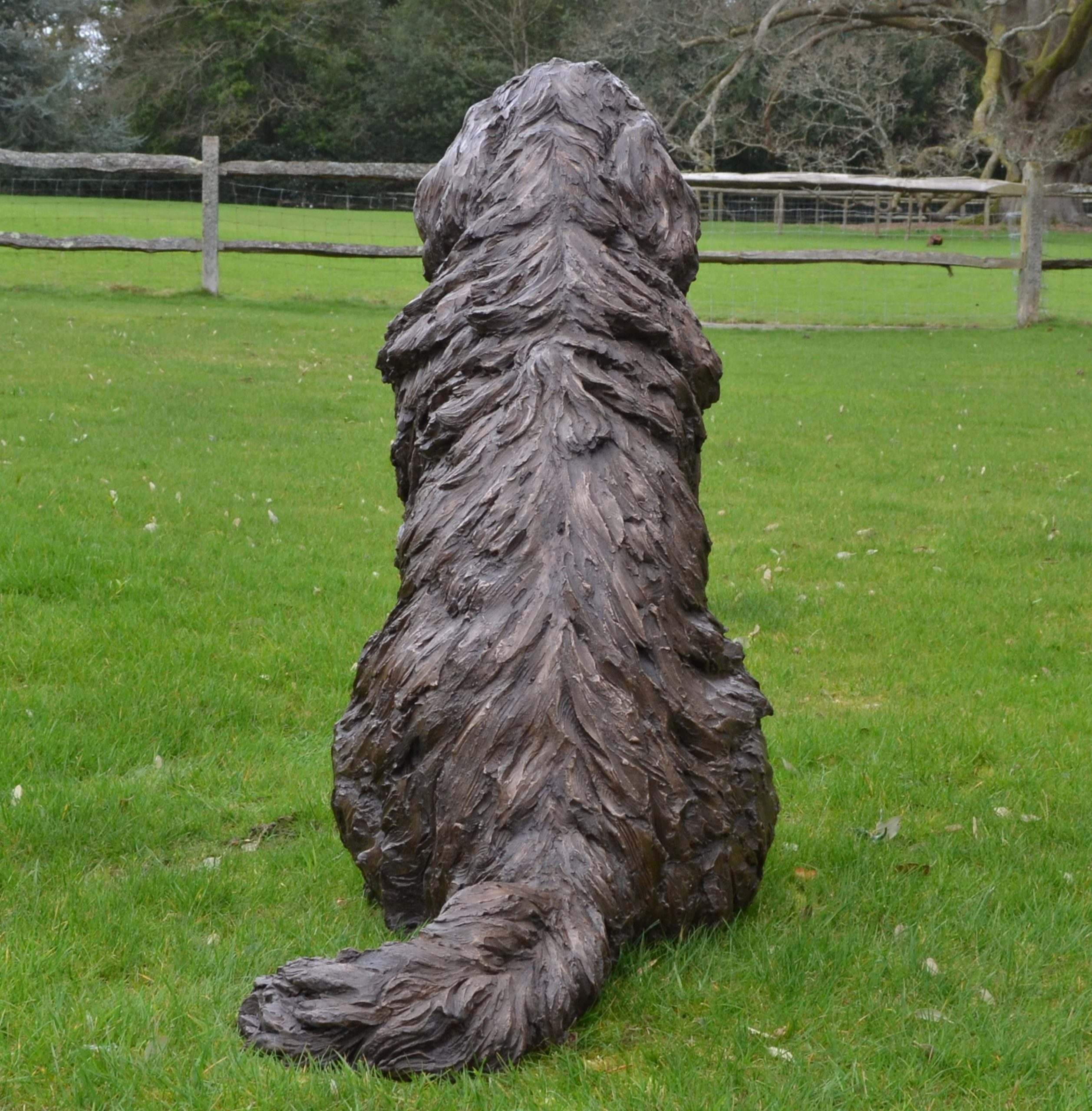 A realism bronze resin sculpture of a newfoundland dog sitting.