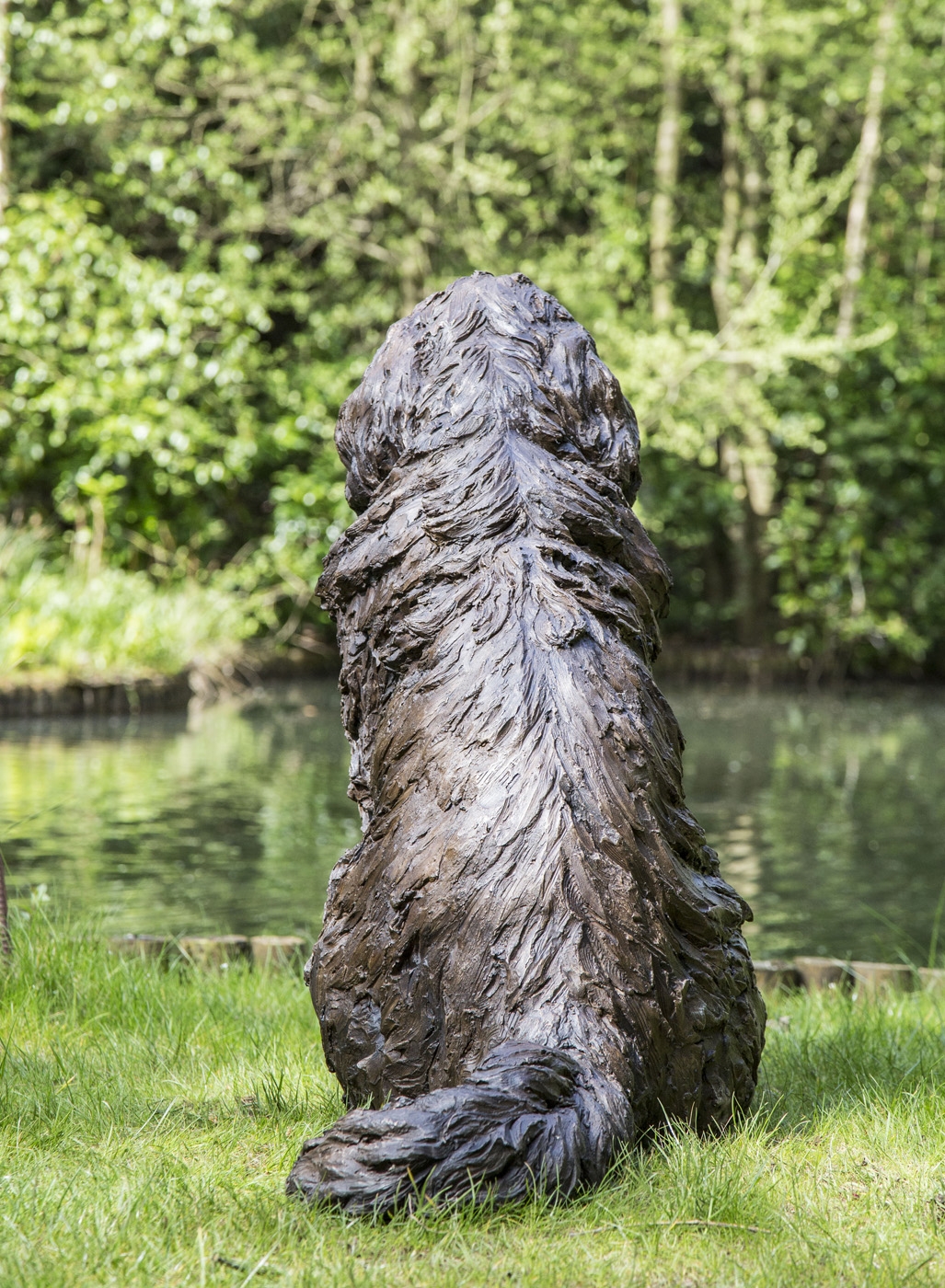 A realism bronze resin sculpture of a newfoundland dog sitting.