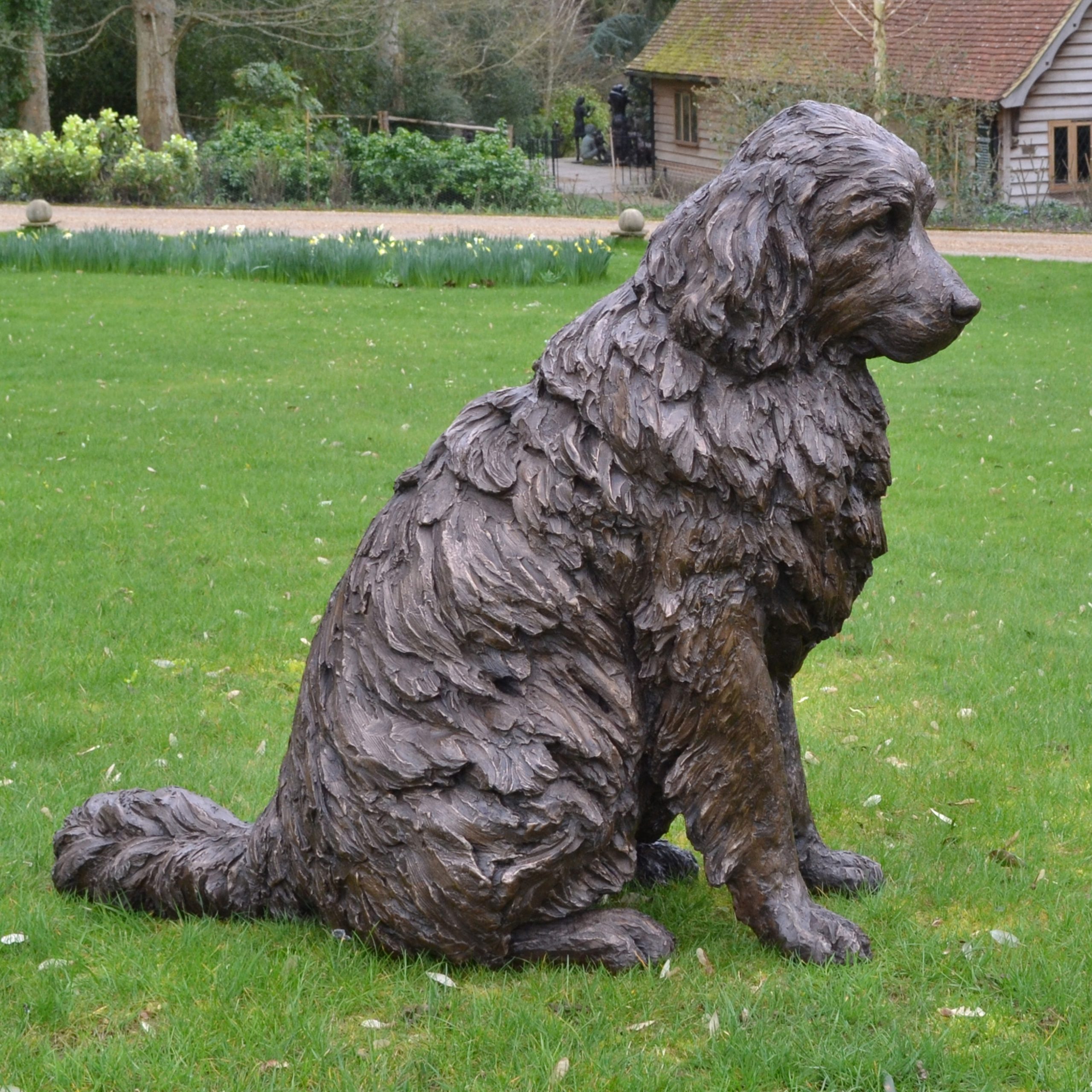 A realism bronze resin sculpture of a newfoundland dog sitting.