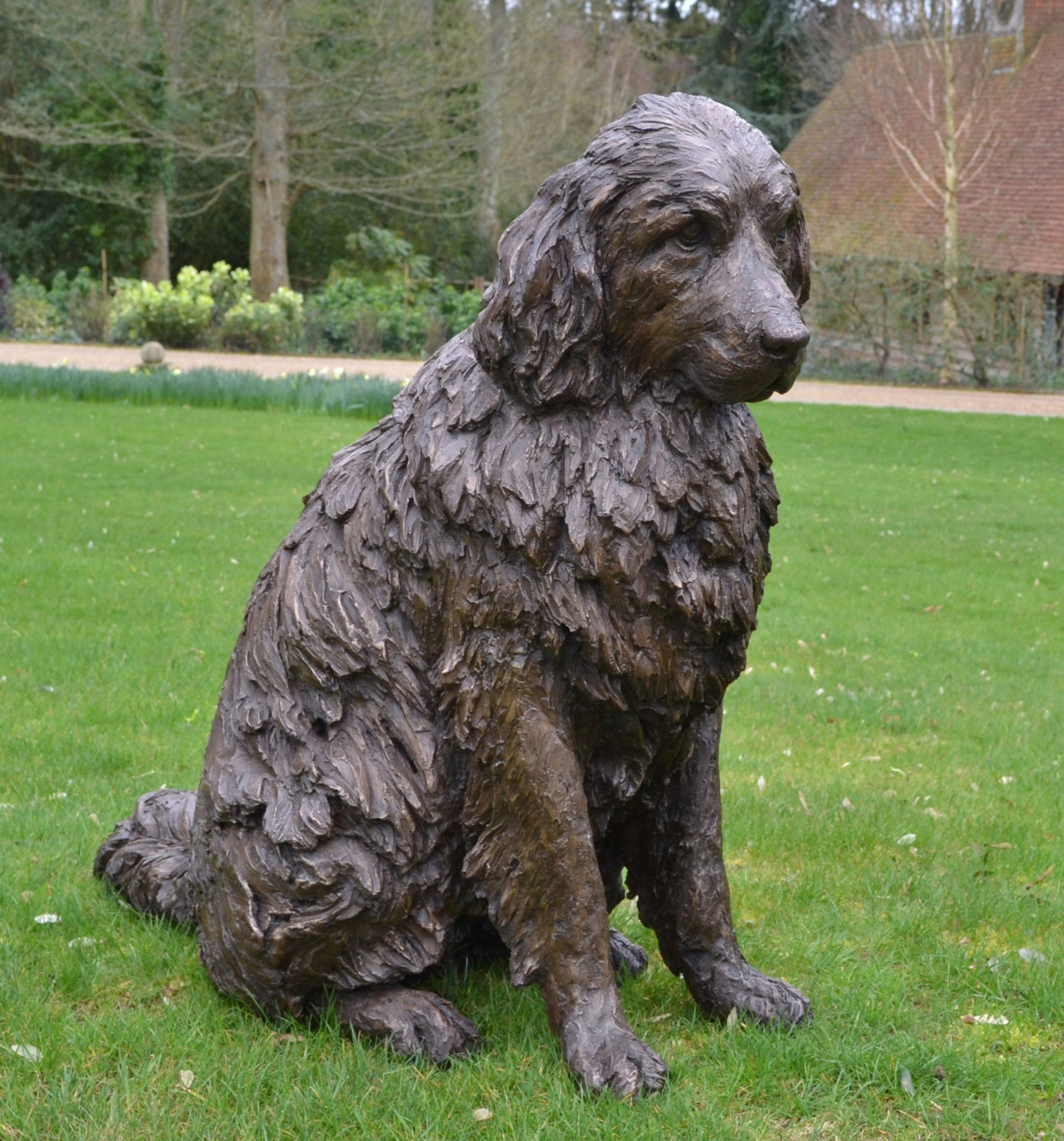 A realism bronze resin sculpture of a newfoundland dog sitting.