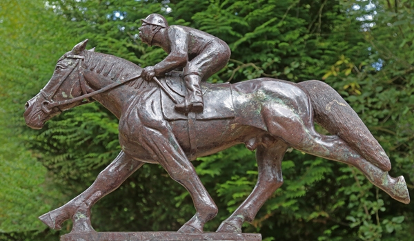 A figurative opal stone sculpture of a race horse with a jockey on its back.