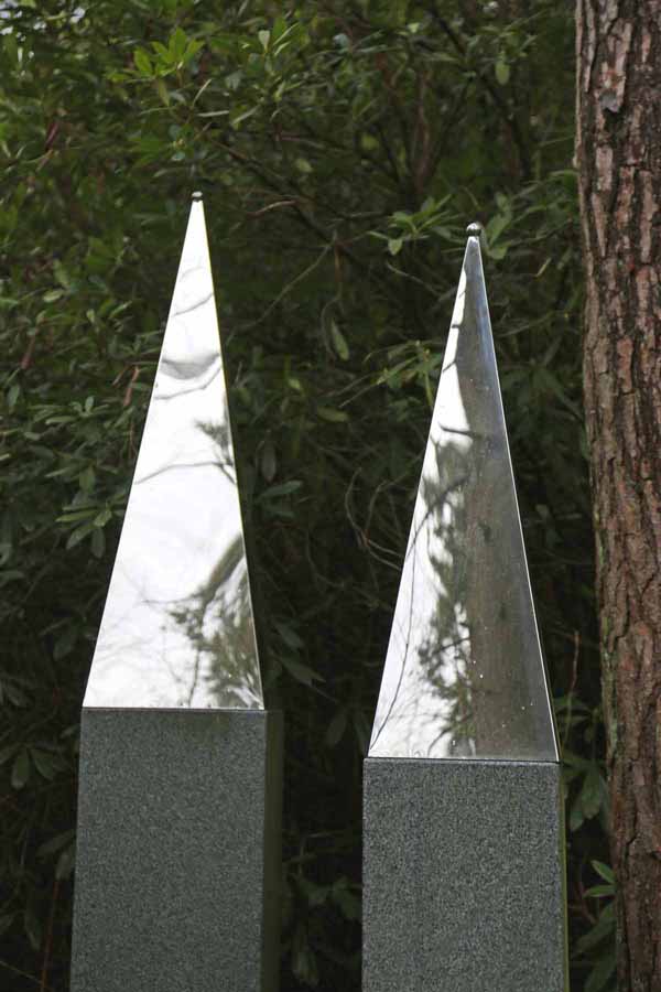 A abstract stainless steel sculpture of a tall and pointed triangular shaped obelisk.