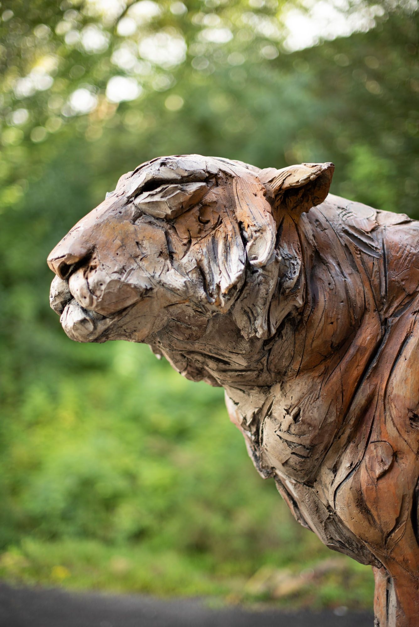 A figurative stoneware ceramic sculpture of a tiger sitting.