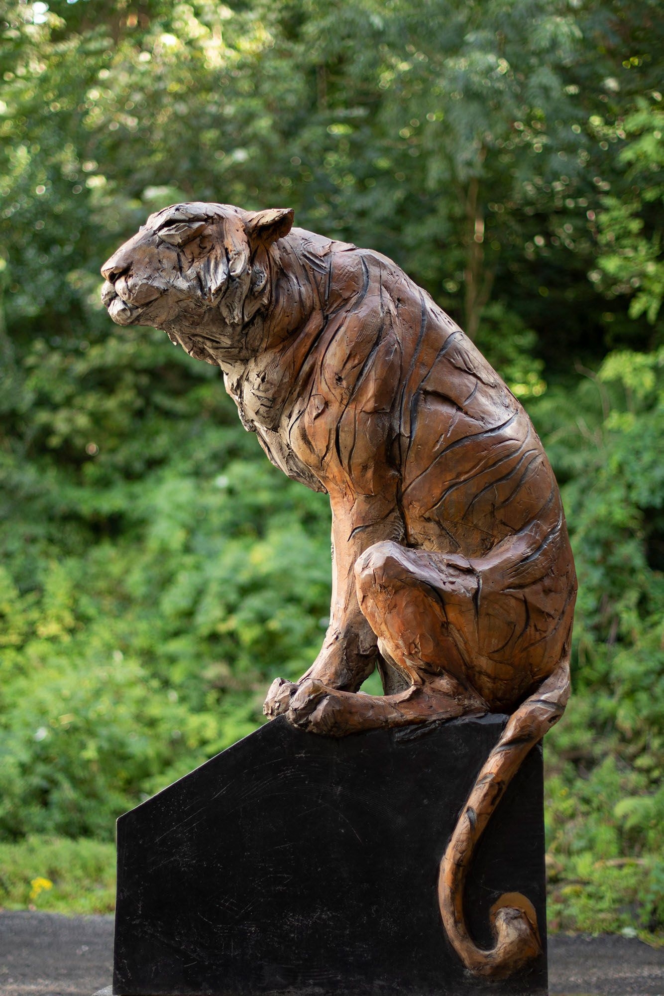 A figurative stoneware ceramic sculpture of a tiger sitting.