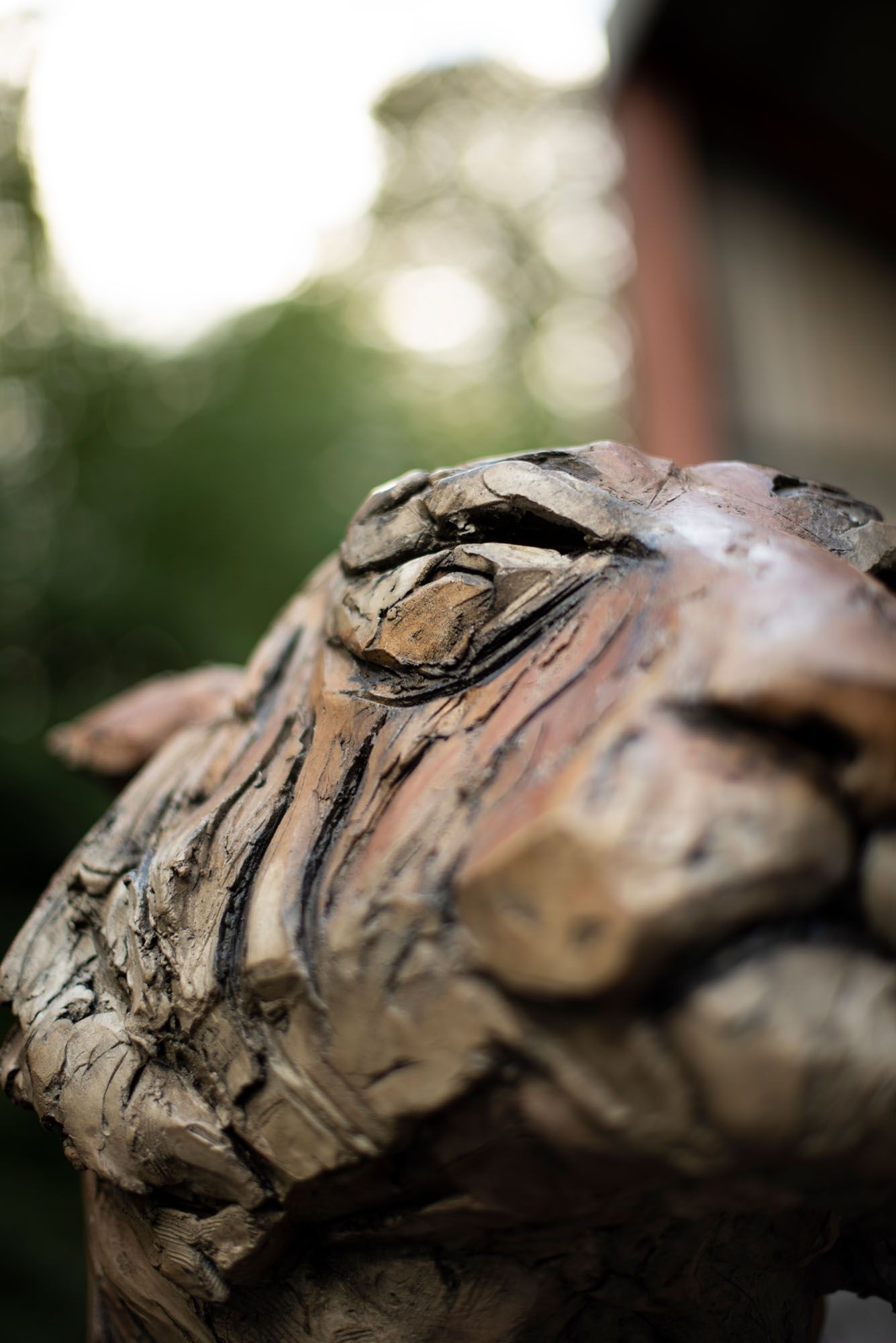 A figurative stoneware ceramic sculpture of a tiger sitting.