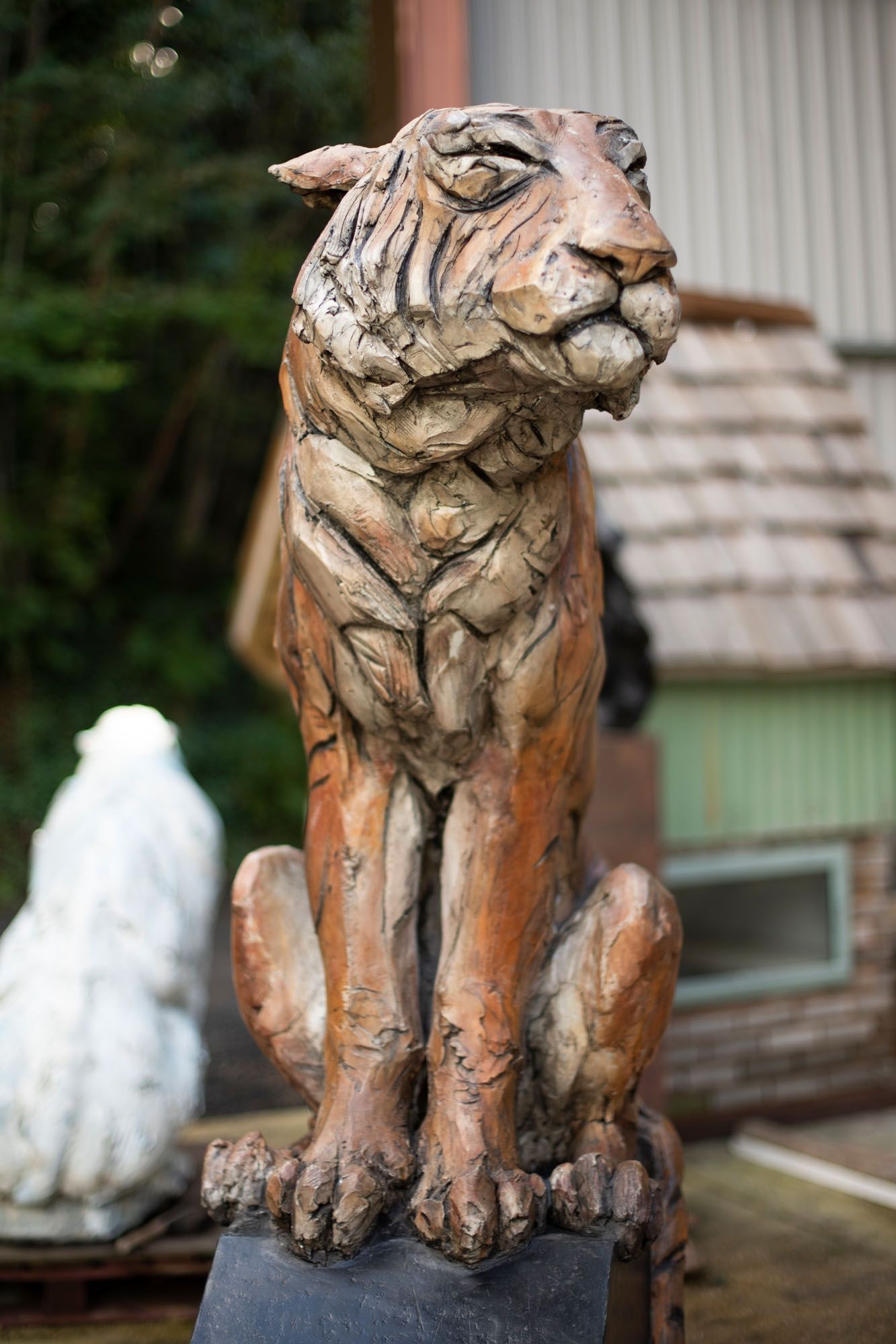 A figurative stoneware ceramic sculpture of a tiger sitting.