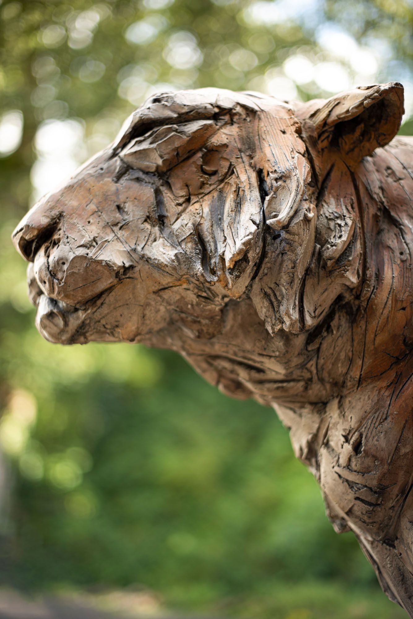A figurative stoneware ceramic sculpture of a tiger sitting.
