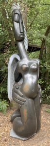A Shona stone sculpture of a woman kneeling with her hands on her hips.