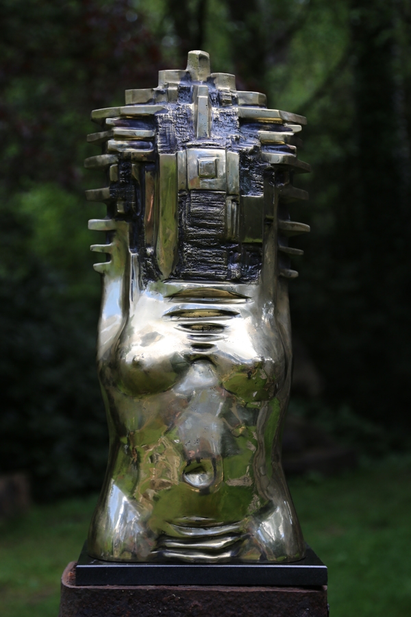 A figurative polished bronze sculpture of a female torso with various abstract shapes on it.