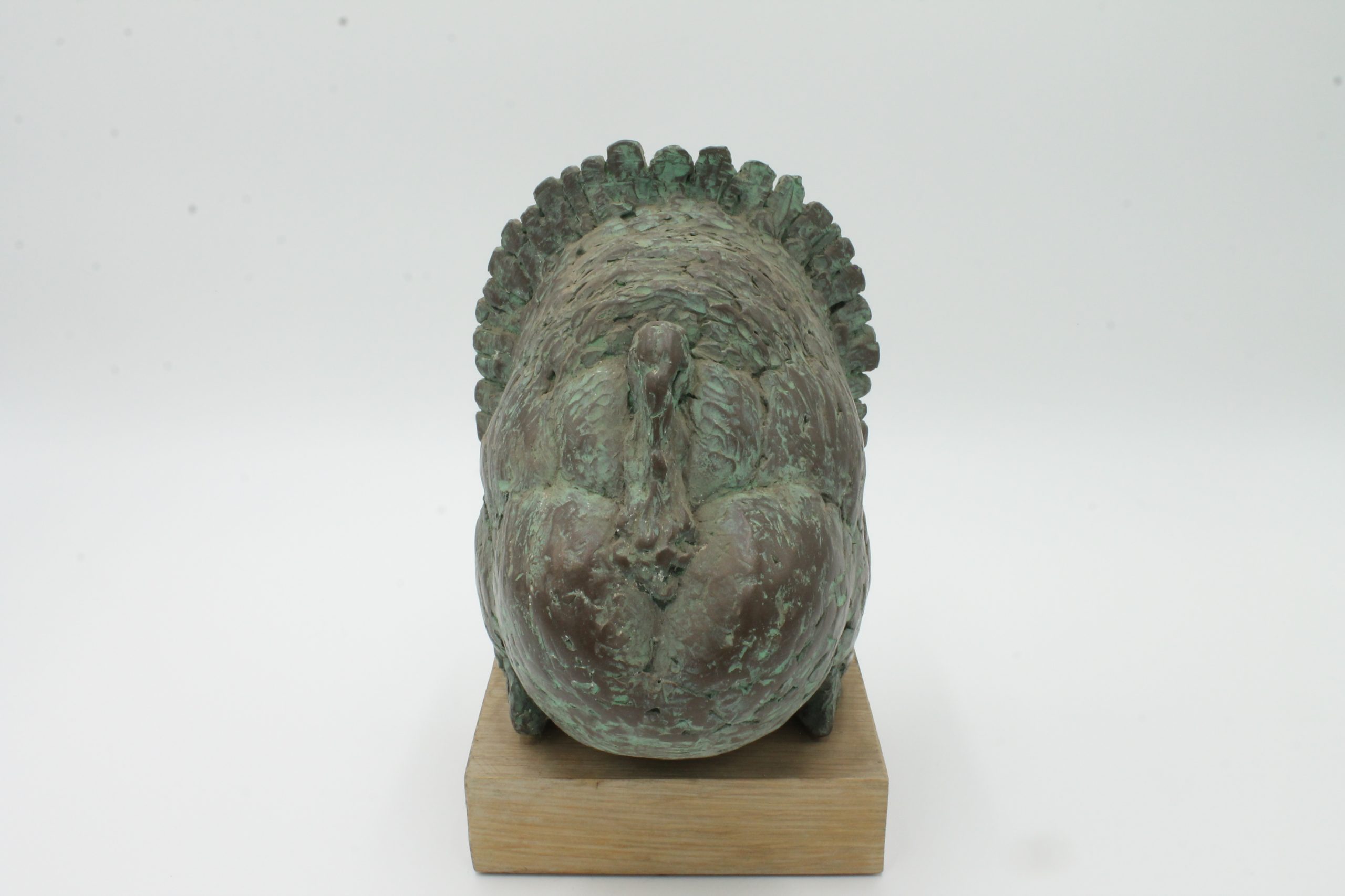 A abstract bronze sculpture of a large turkey standing with its feathers on display.