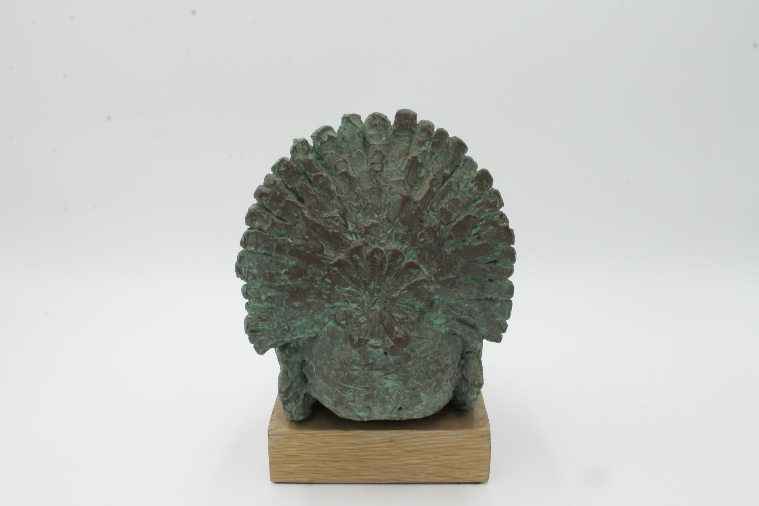 A abstract bronze sculpture of a large turkey standing with its feathers on display.