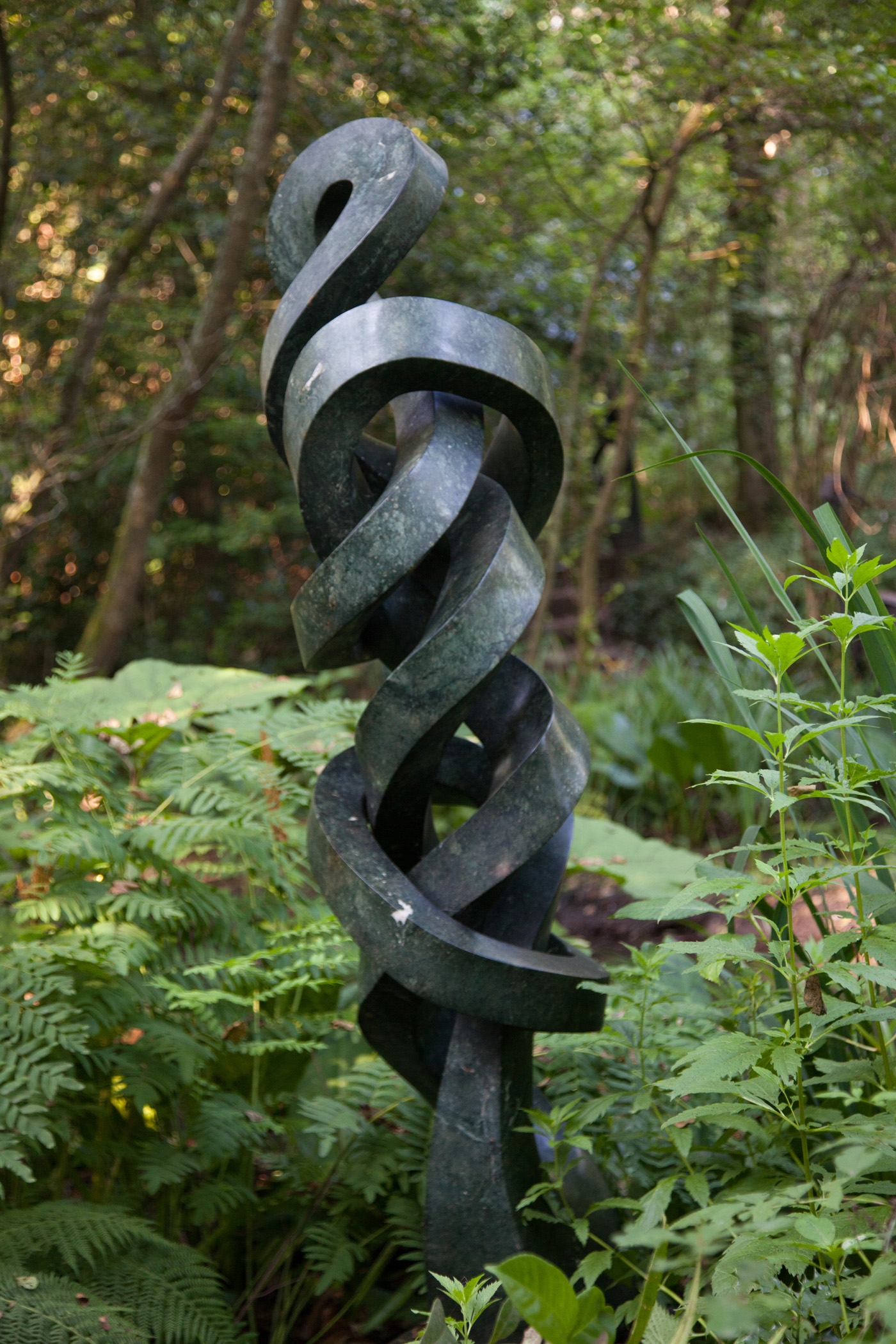 An abstract Shona sculpture of tall twirling shapes, intertwined within themselves. Made of Opal stone.