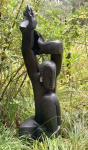 A shona springstone sculpture of a man raising his arms above his head.