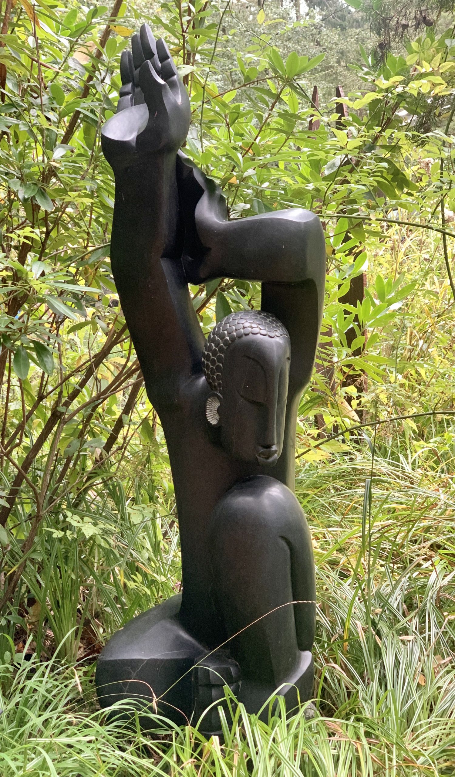A shona springstone sculpture of a man raising his arms above his head.