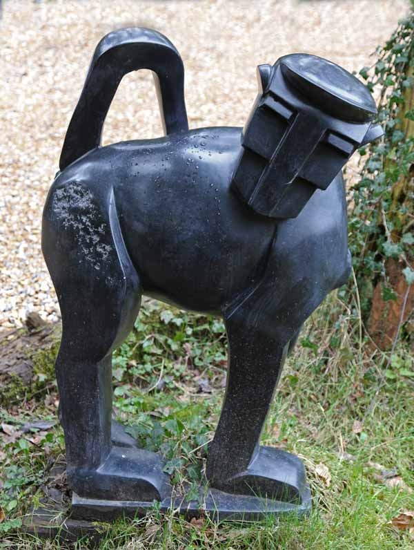 A contemporary stone sculpture of a baboon standing on top of a slab.