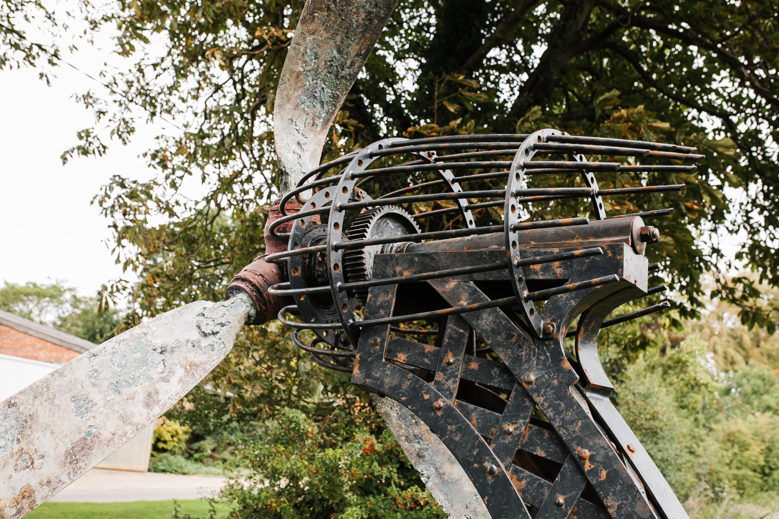 A architectural found object sculpture of a plane propeller mounted onto a metal frame.
